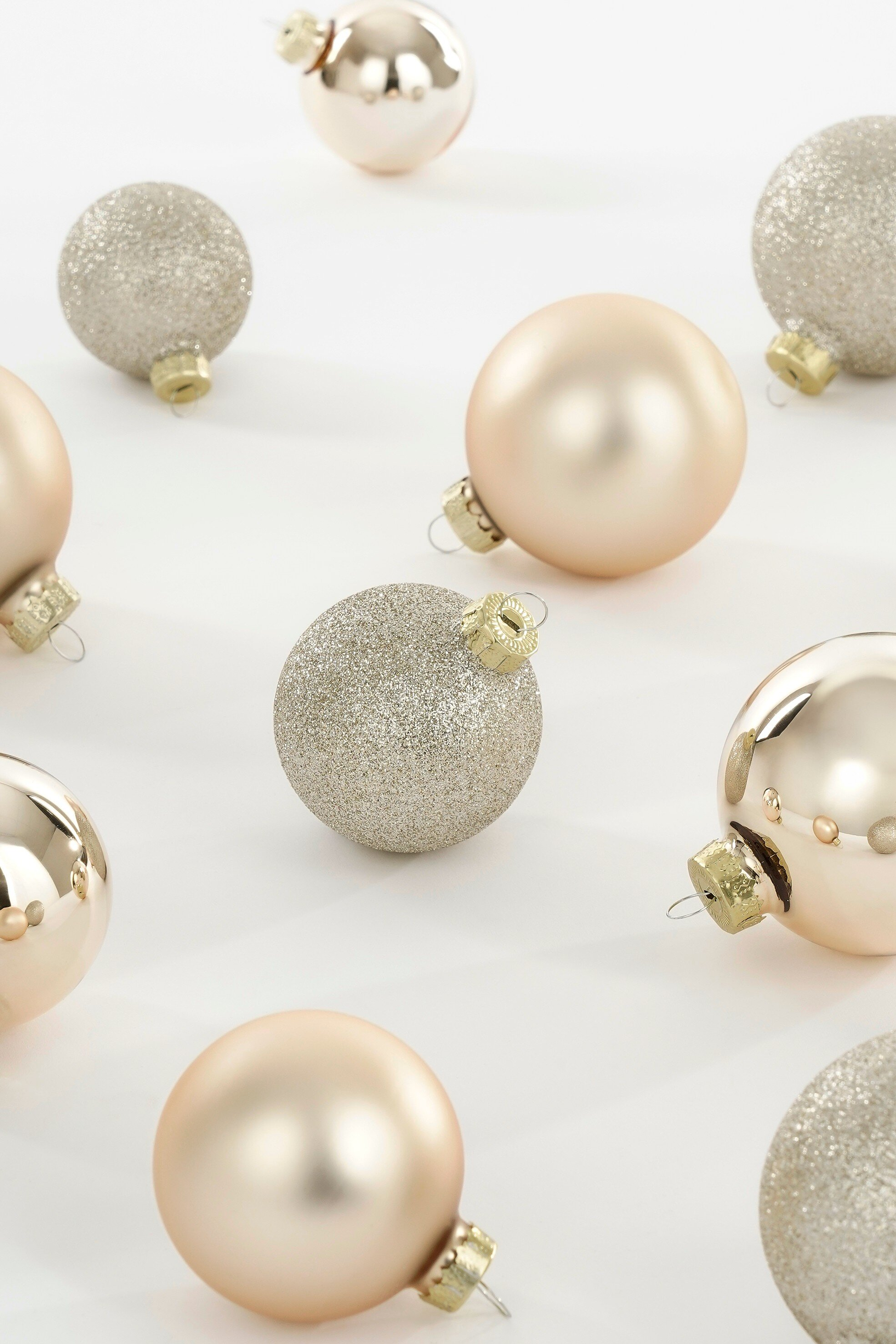 L'image montre plusieurs décorations de Noël sur une surface blanche. Certains sont lisses, d'autres brillants.