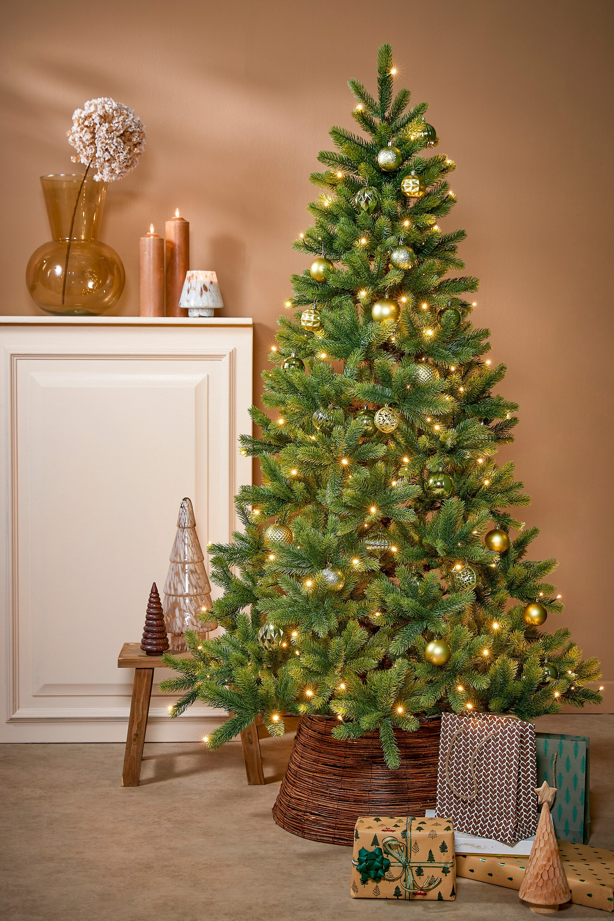 Un sapin de Noël décoré avec des ornements et des lumières. Des cadeaux sont sous l'arbre. Des bougies et un vase sont également visibles.