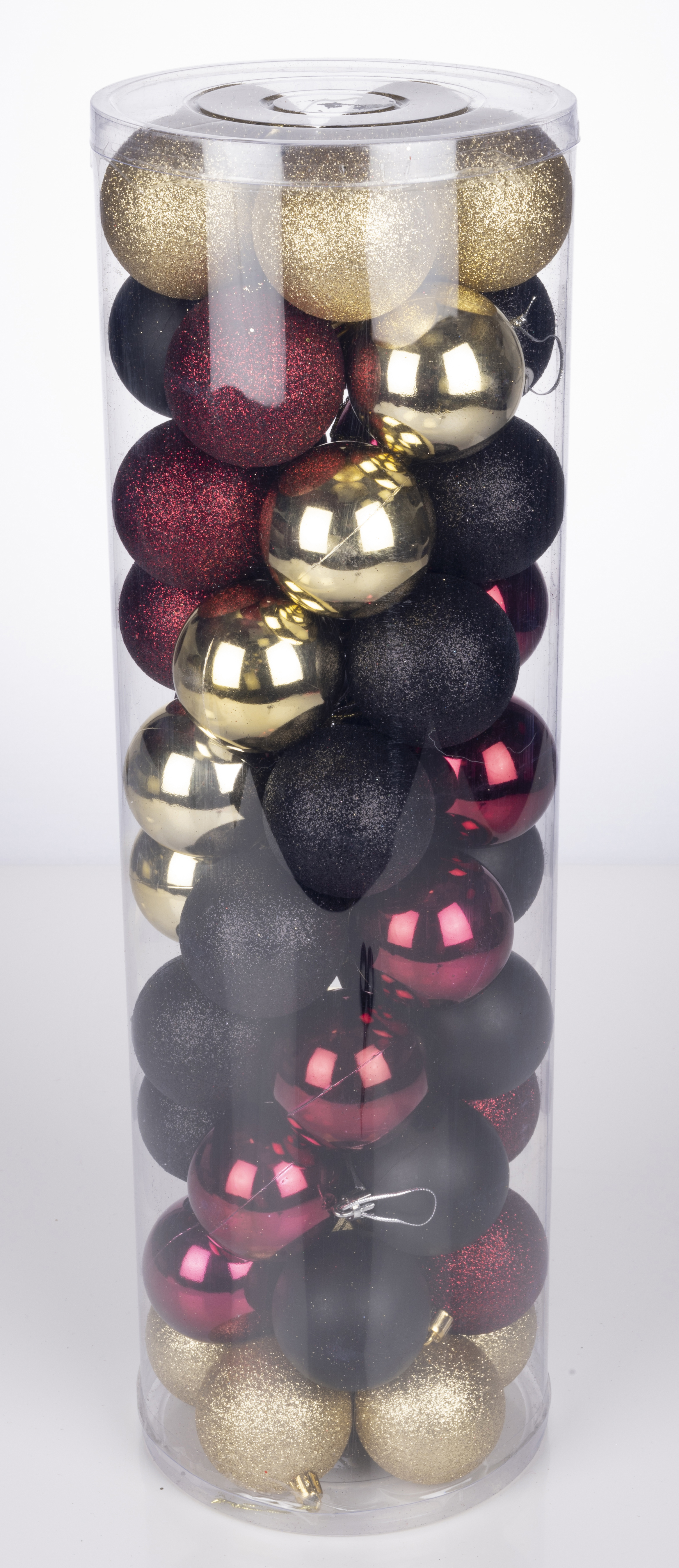 Un tube en plastique transparent rempli de décorations de Noël dorées, rouges et noires.