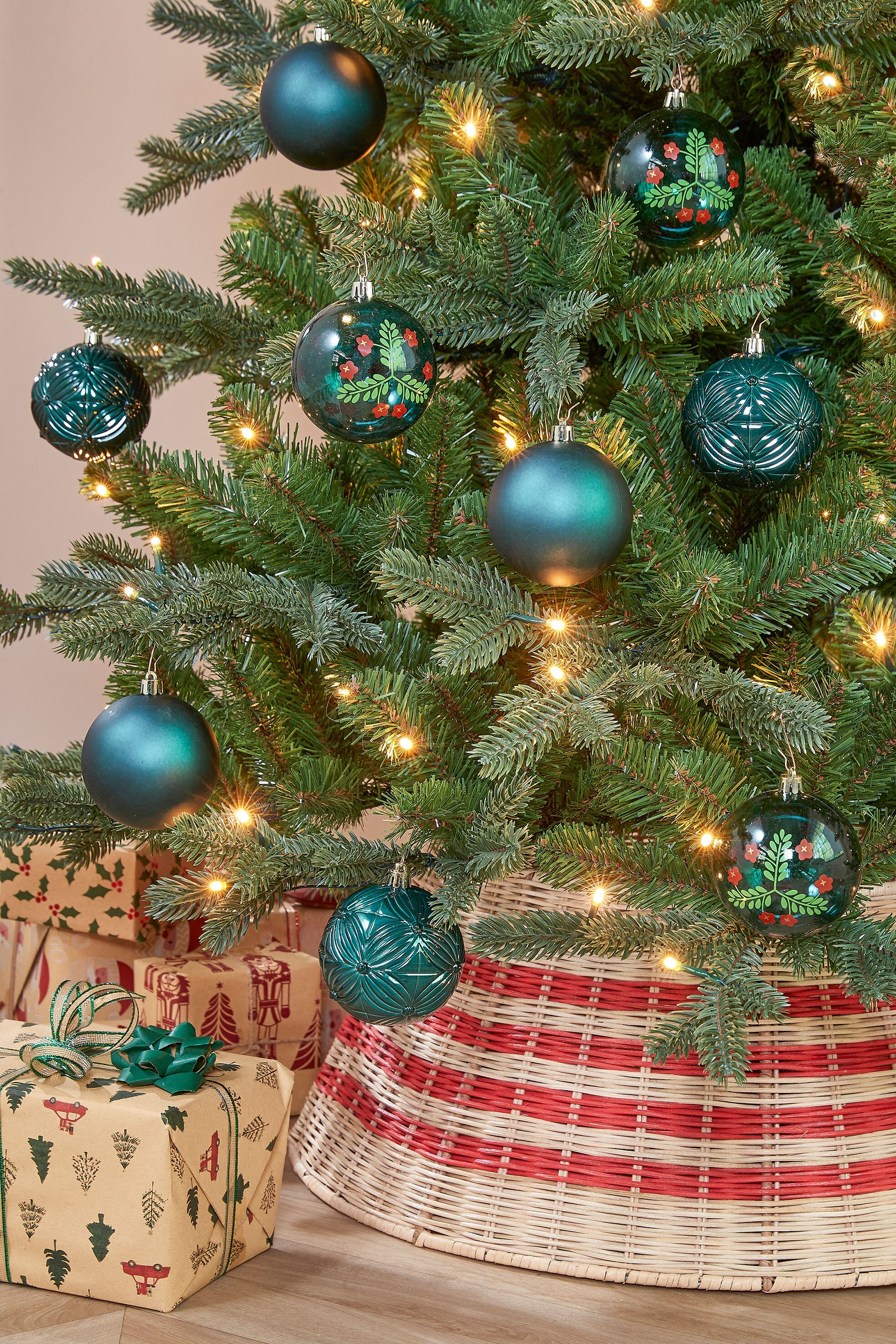 Un sapin de Noël décoré avec des ornements, des lumières et des cadeaux. Une jupe d'arbre entoure la base.