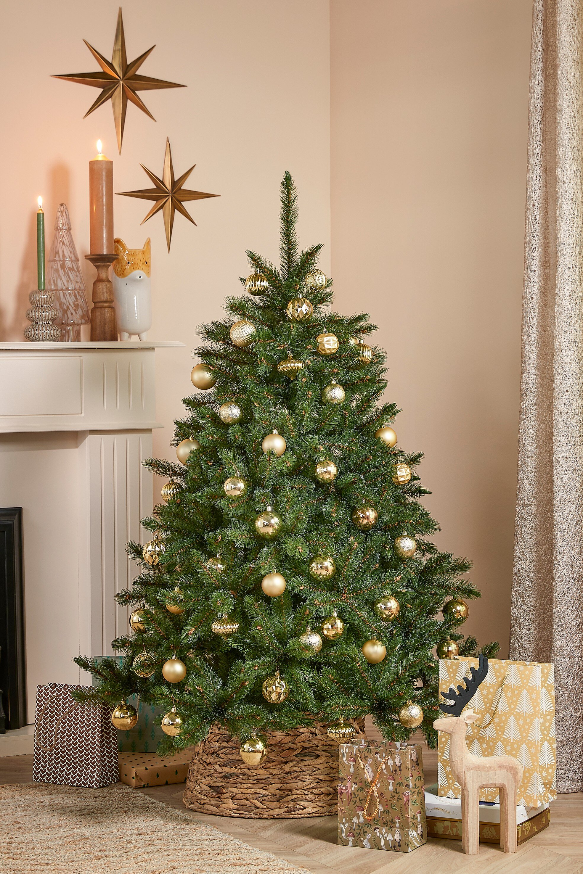 Sapin de Noël décoré d'ornements dorés. Cadeaux, décorations en étoile et renne en bois sont présents.