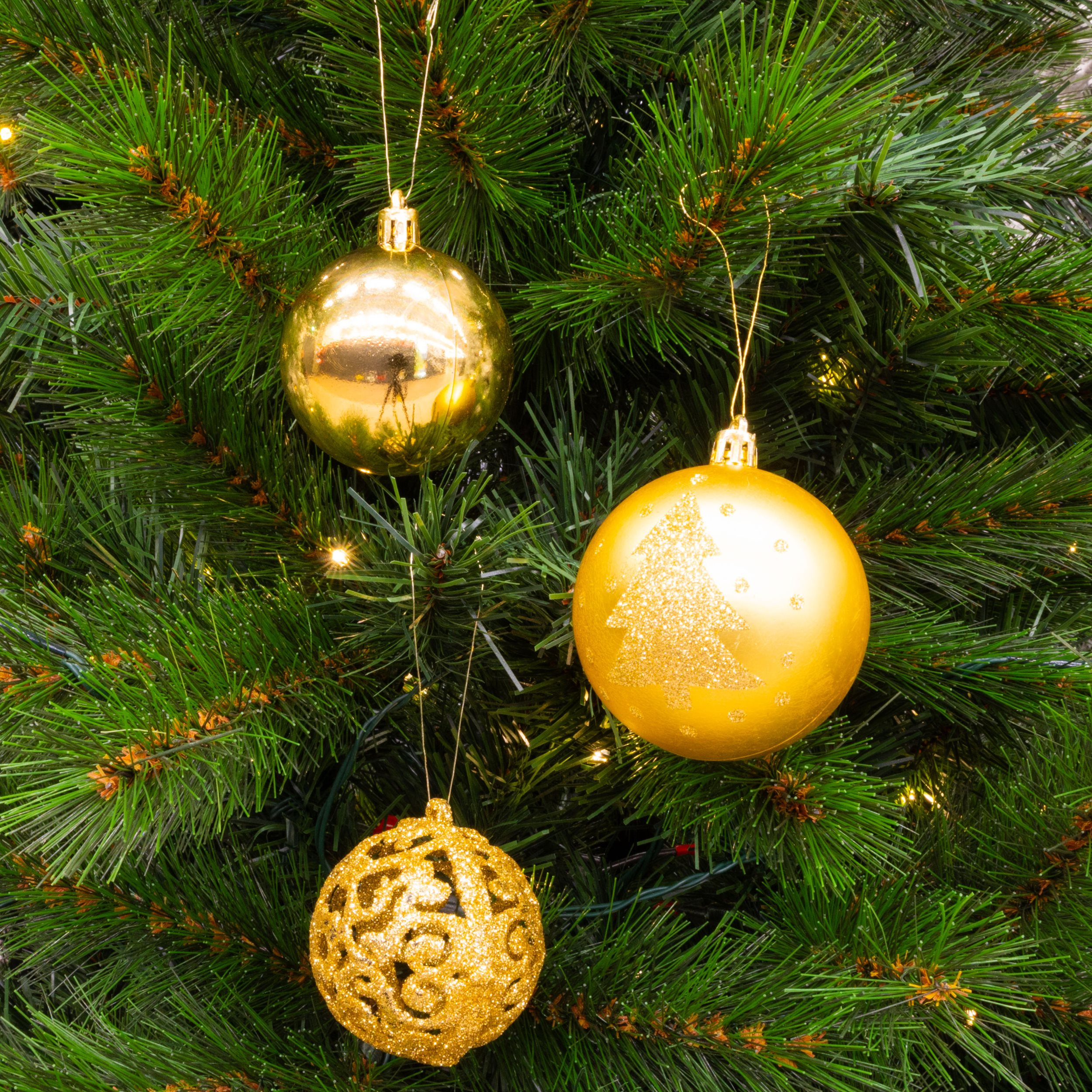 Gros plan sur un sapin de Noël avec trois ornements dorés. L'arbre est vert avec de petites lumières.