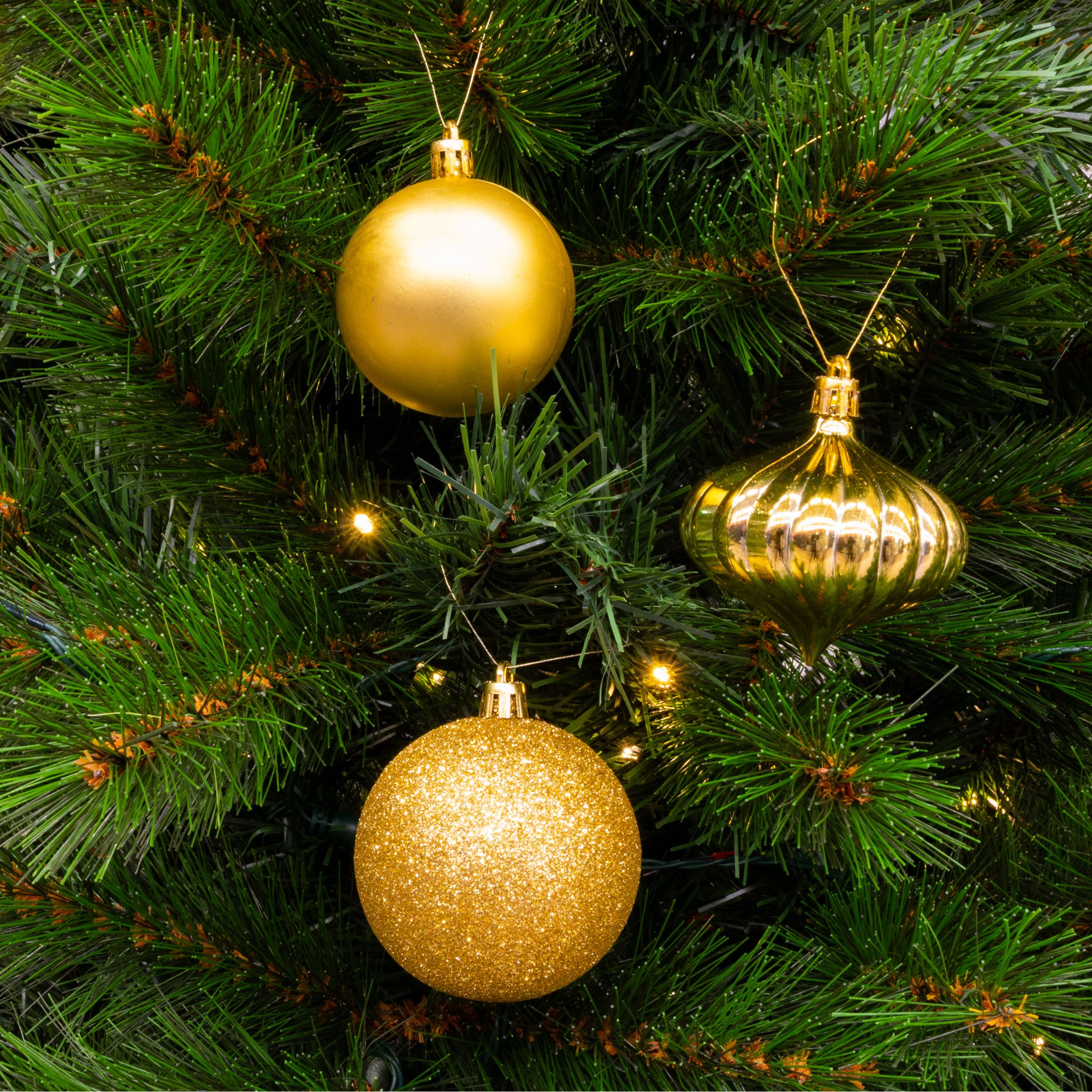 Un sapin de Noël avec trois ornements dorés. L'arbre est vert avec de petites lumières.