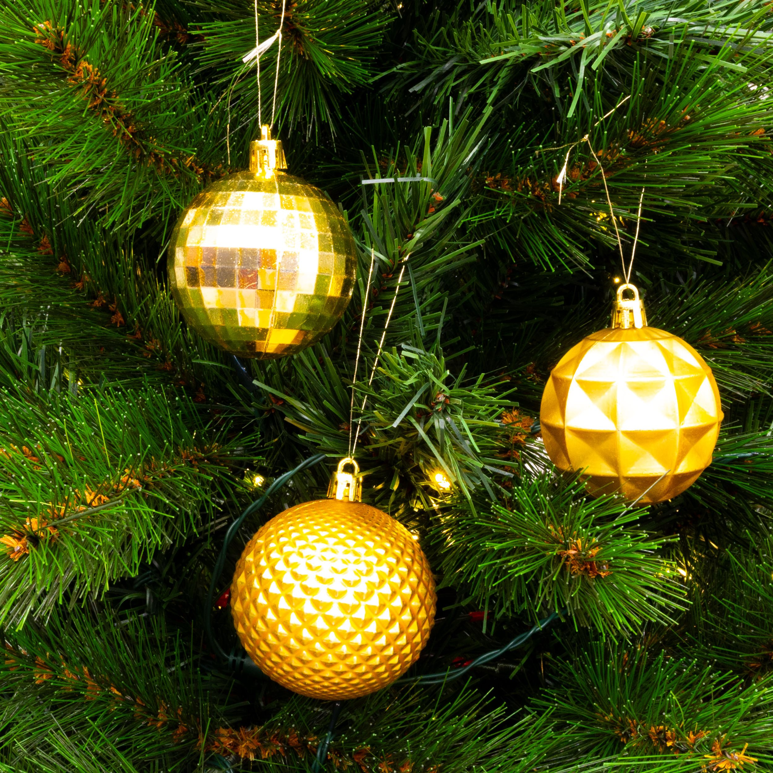 Gros plan sur un sapin de Noël avec trois ornements dorés. L'arbre est vert avec des aiguilles visibles.