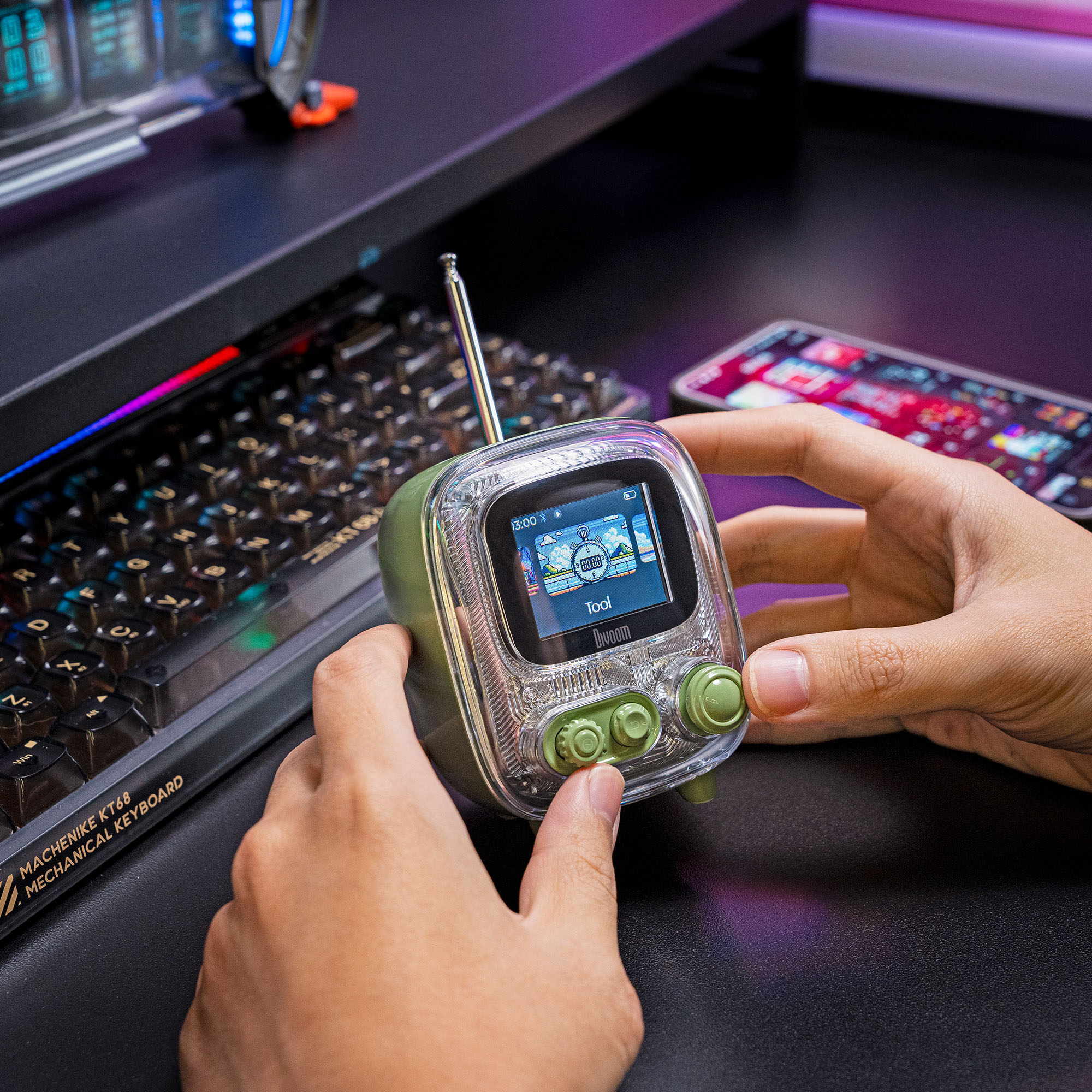 Eller, bir alet gösteren bir ekranı olan yeşil bir retro radyo tutuyor. Arka planda bir telefon ve klavye var.