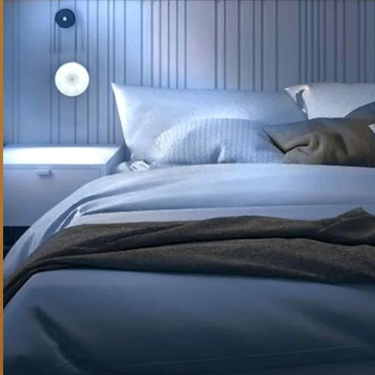 Schlafzimmer mit blauem Bett, grauer Decke, runden Wandleuchten und Nachttisch.