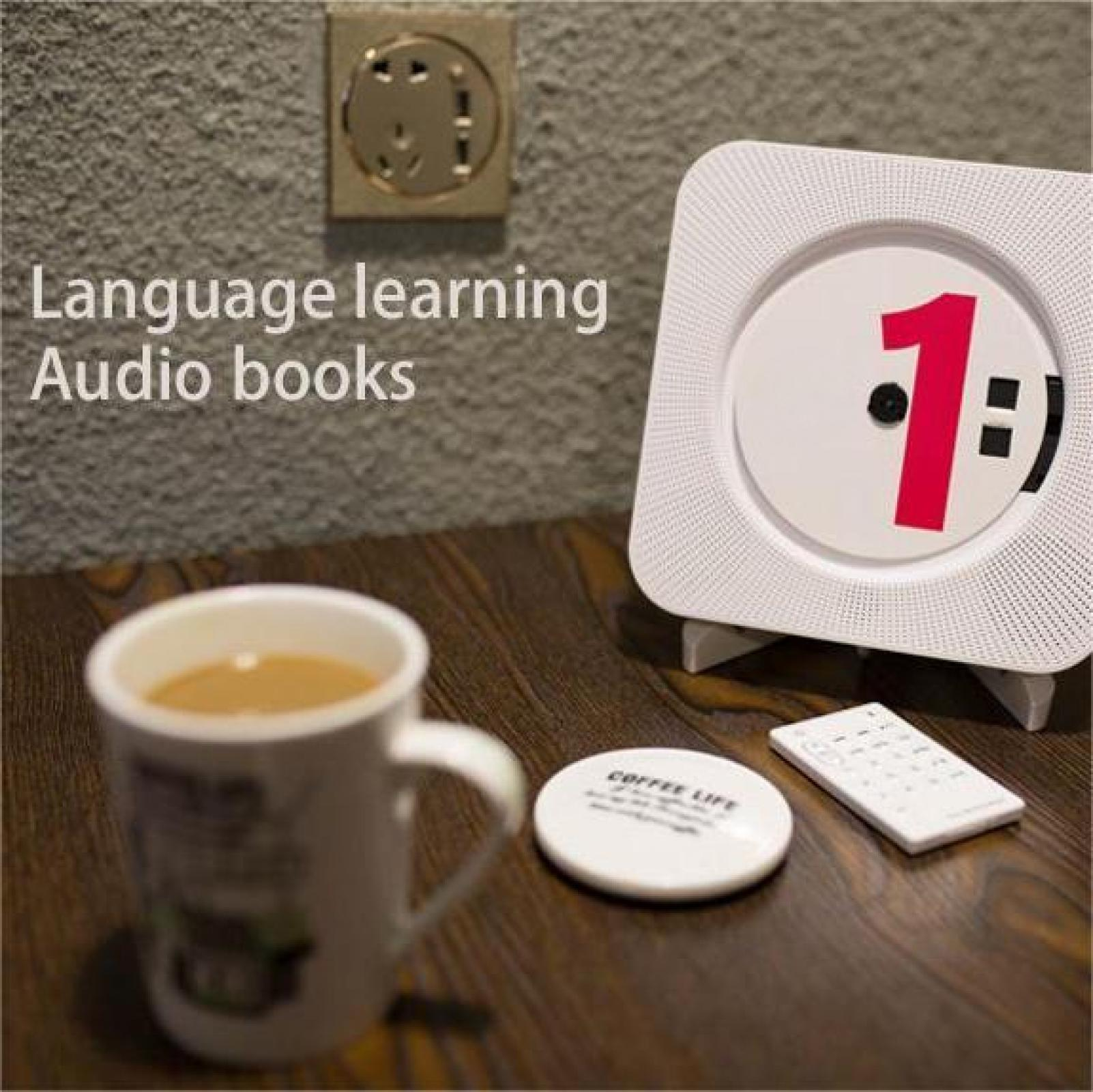 Ein weißer CD-Player mit einer roten '1', eine Kaffeetasse, Fernbedienung und Untersetzer auf einem Holztisch.
