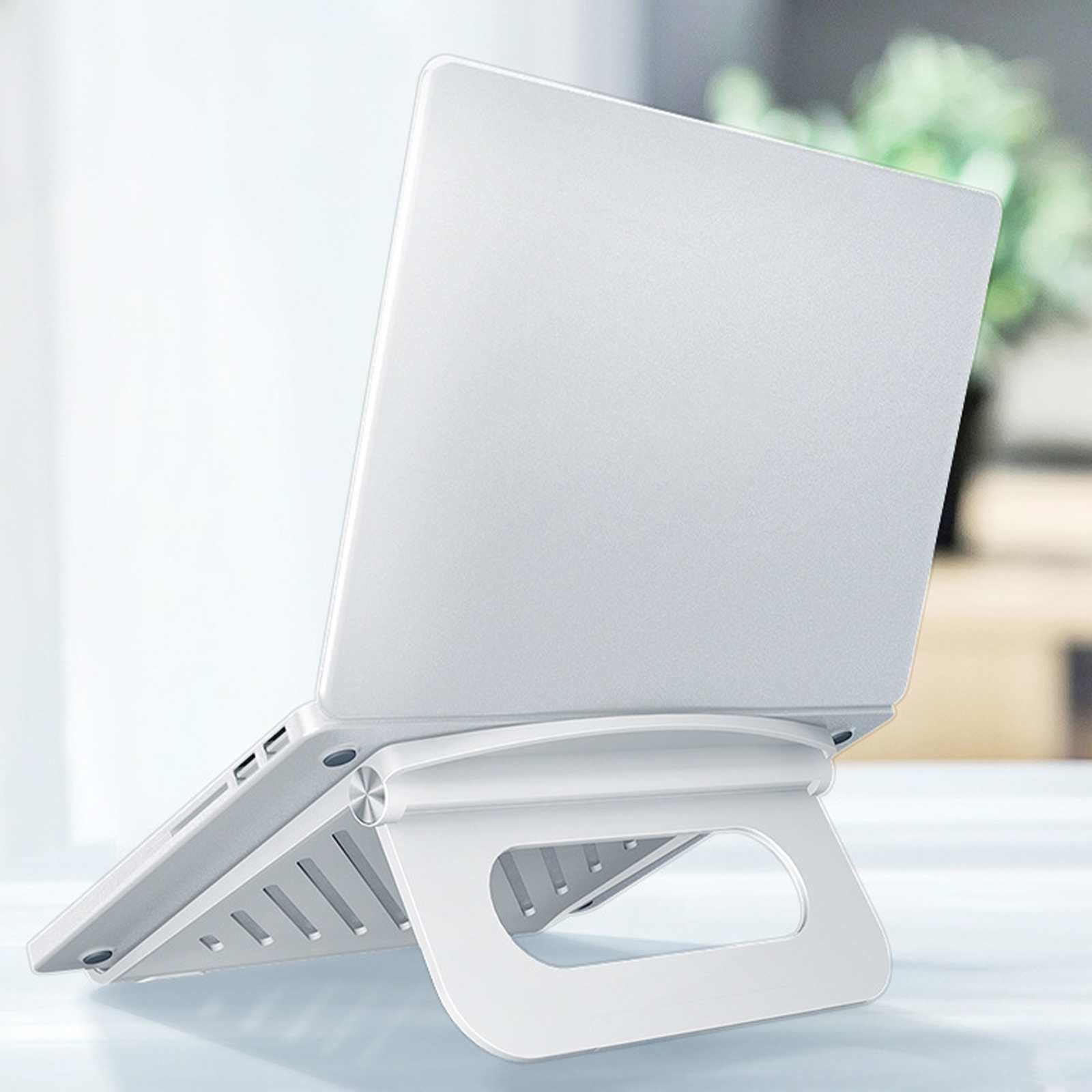 Ein weißer Laptop auf einem weißen Laptopständer. Der Ständer ist abgewinkelt und hat ein hohles Design. Der Hintergrund ist unscharf.
