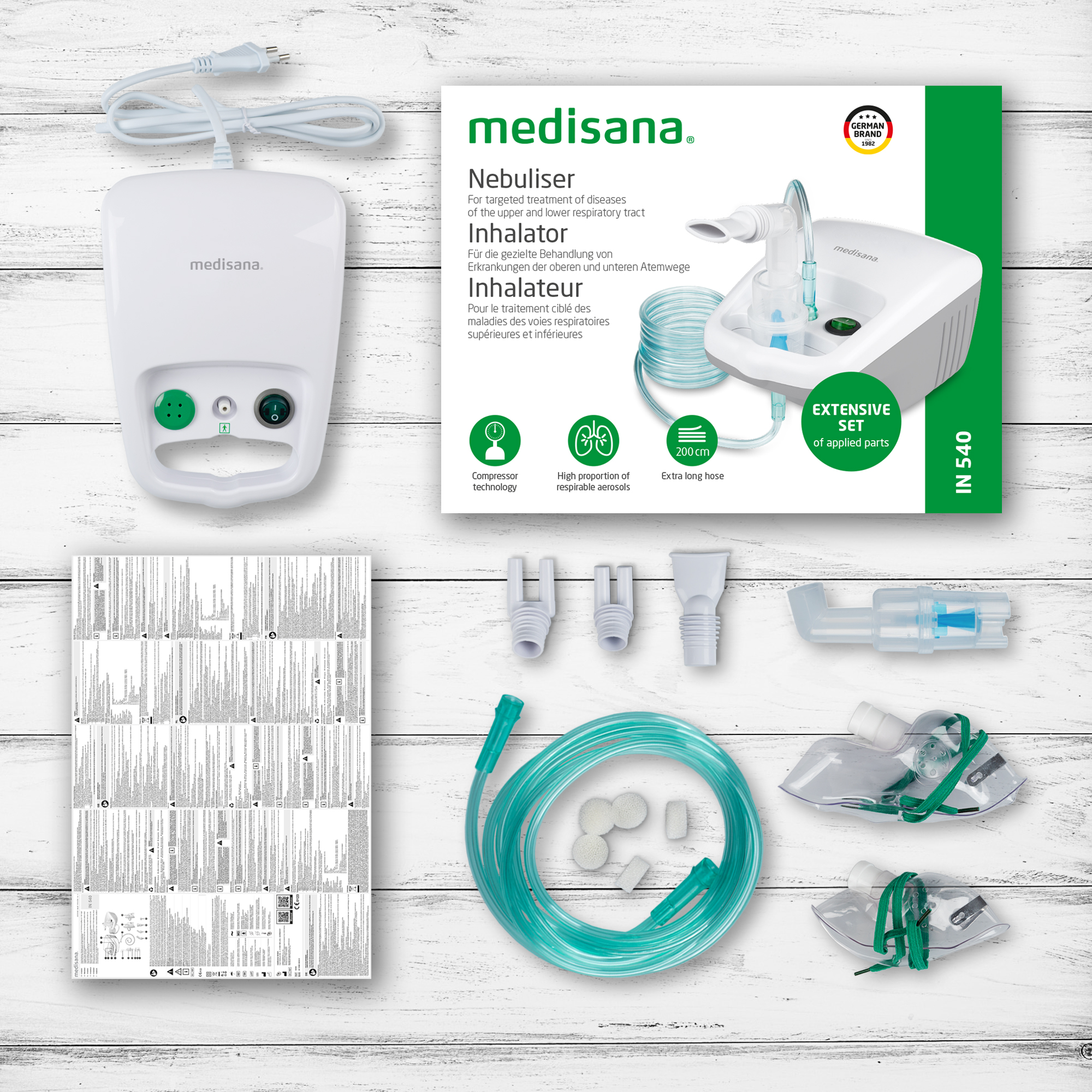 Un kit nébuliseur medisana blanc avec accessoires, y compris des masques, des tubes et des instructions, sur une surface en bois.