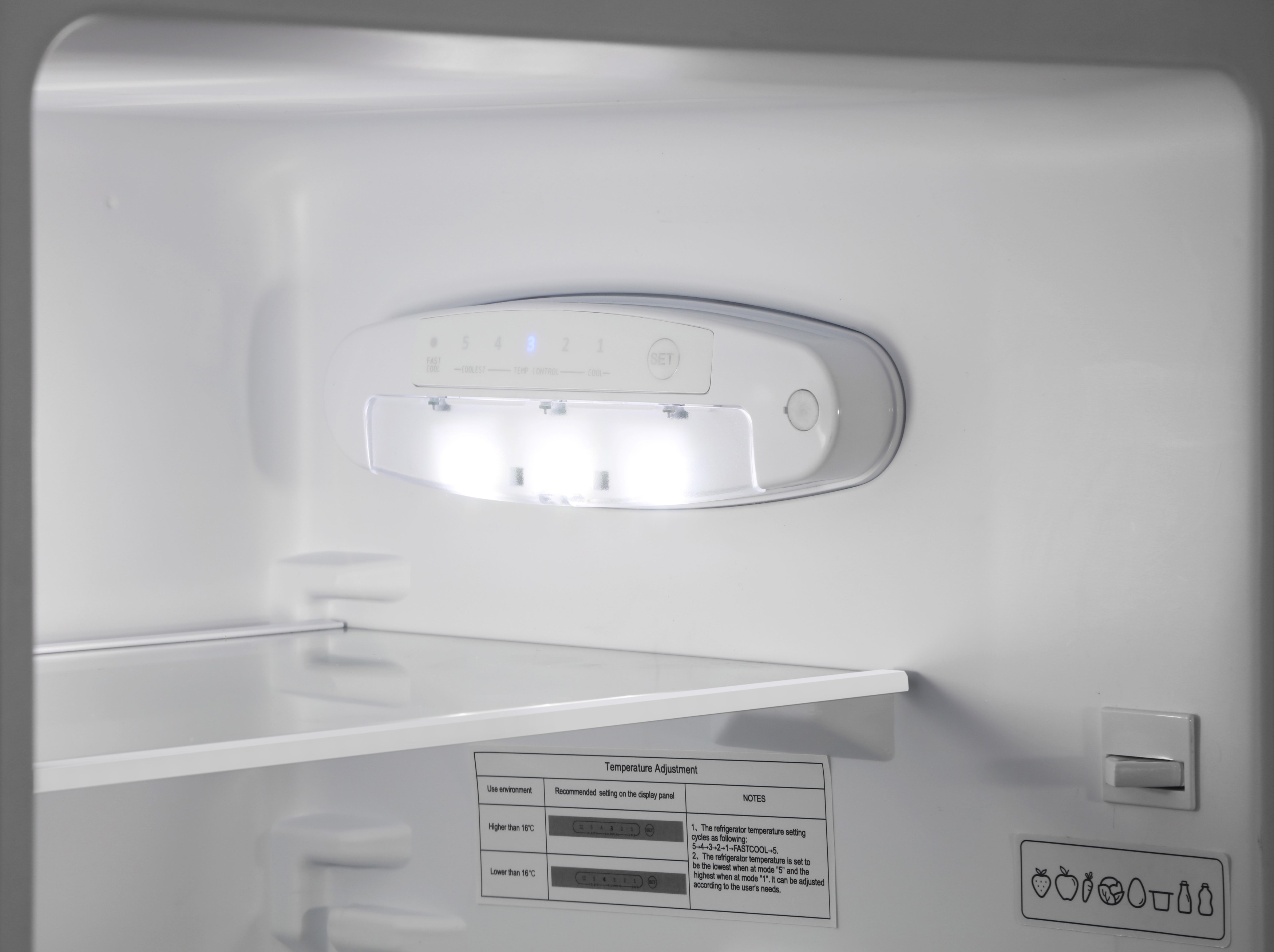 In einem weißen Kühlschrank. Ein Bedienfeld mit Lichtern und ein Regal sind sichtbar. Text beschreibt Temperatureinstellungen.