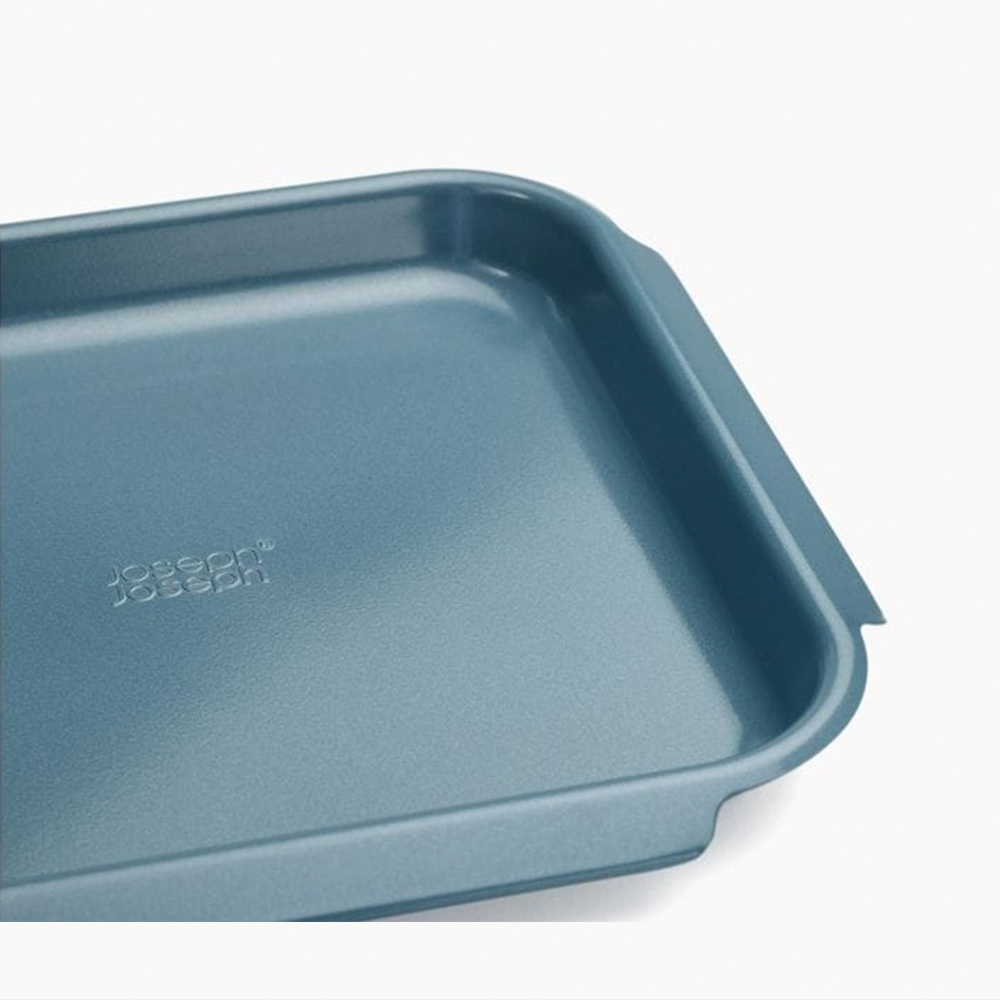 Nahaufnahme eines teal-farbenen Backblechs mit abgerundeten Kanten und dem Markennamen 'Joseph Joseph'.
