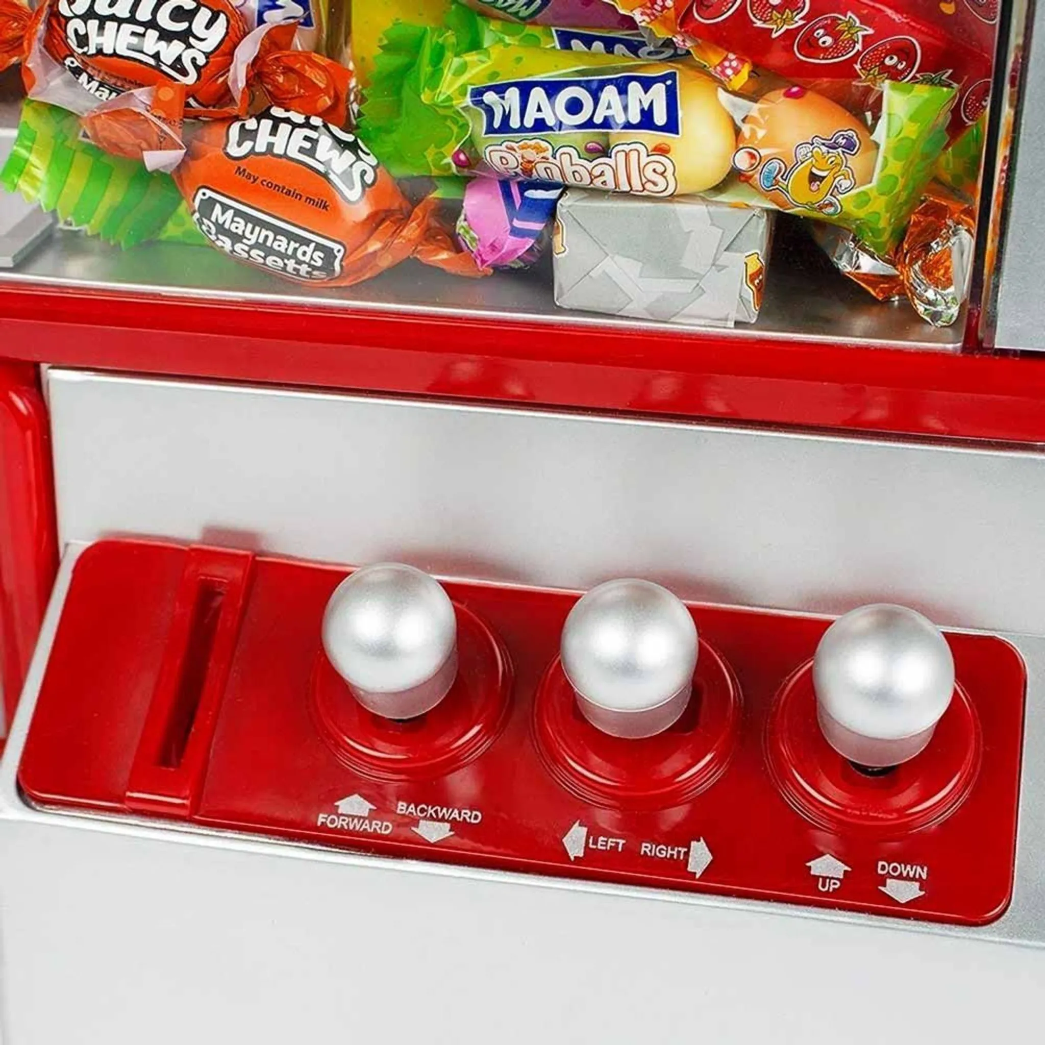 Süßigkeitenautomat mit bunten Süßigkeiten durch ein klares Fenster. Rotes Bedienfeld mit silbernen Joysticks.