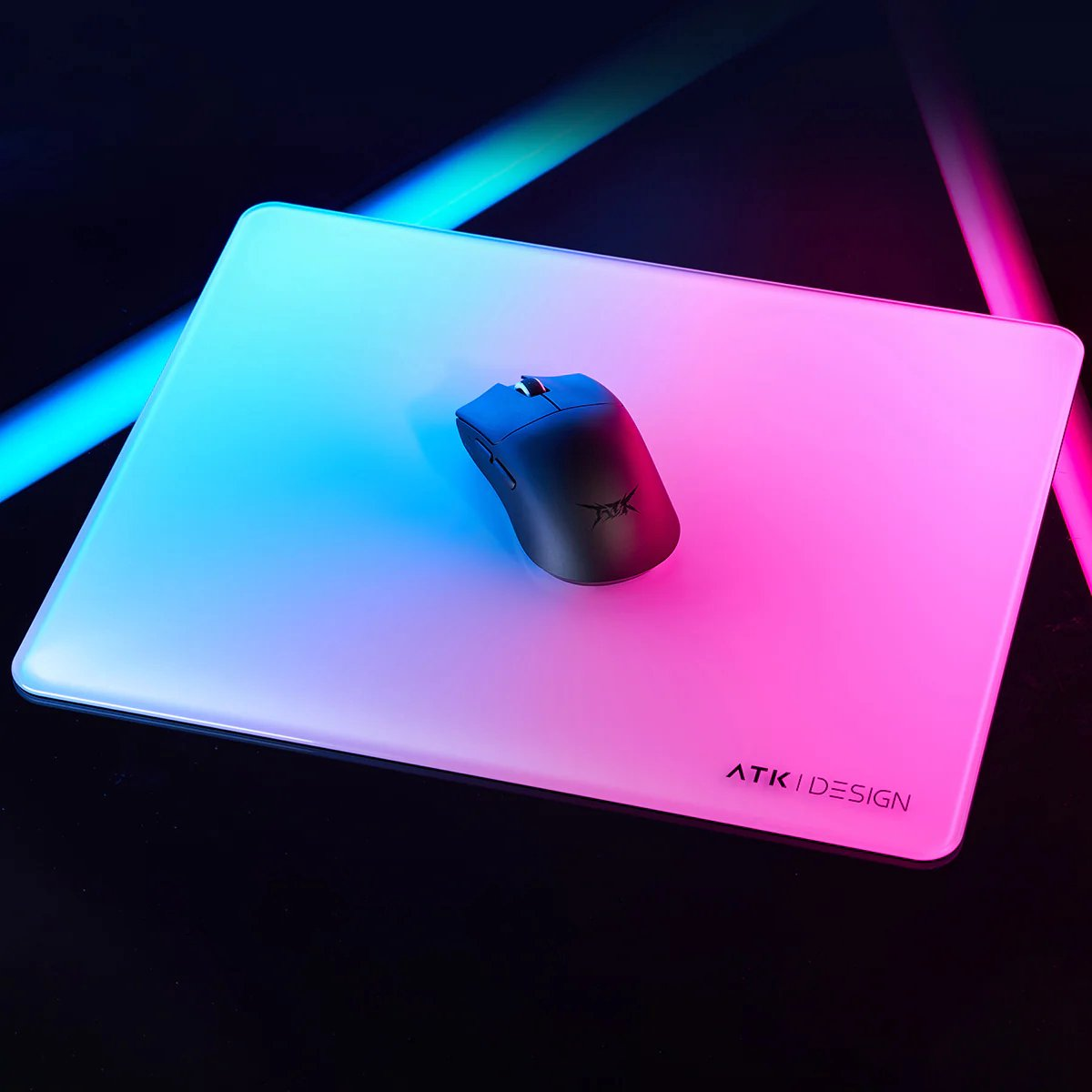 Zwarte muis op een muismat met blauw naar roze verloop, met ATK I DESIGN tekst. Zwarte achtergrond en neonlichten.