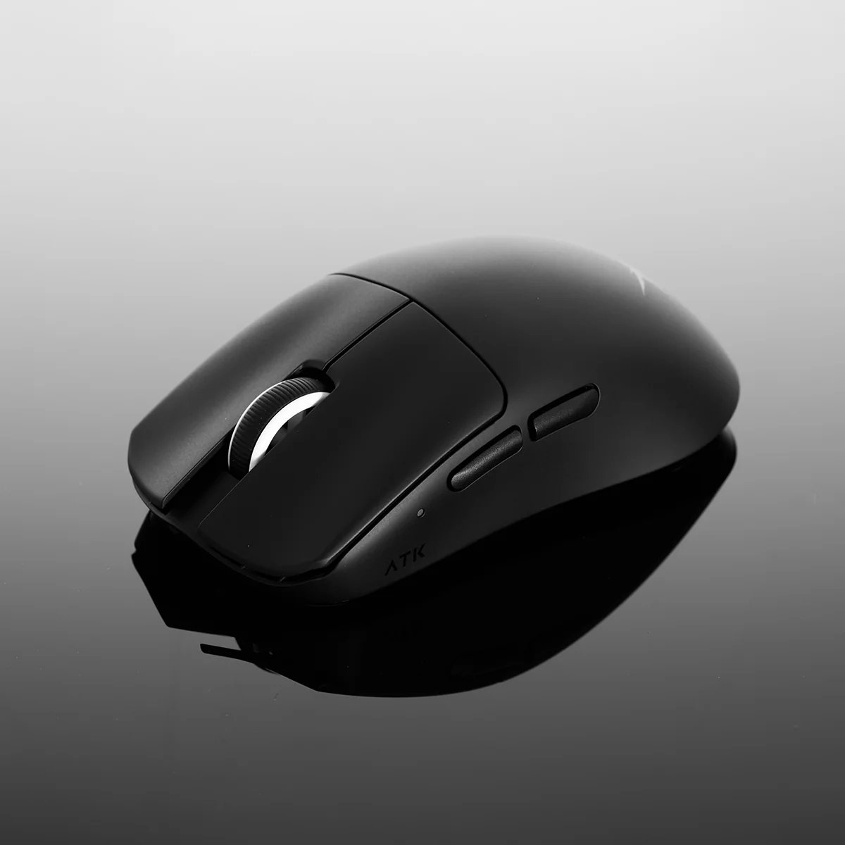 Un ratón de ordenador negro con rueda de desplazamiento y botones laterales se muestra sobre una superficie brillante y reflectante.