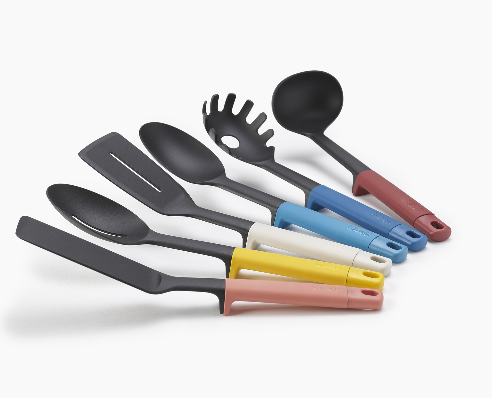 Juego de utensilios de cocina negros con mangos de colores: rosa, amarillo, blanco, azul y rojo, dispuestos sobre fondo blanco.