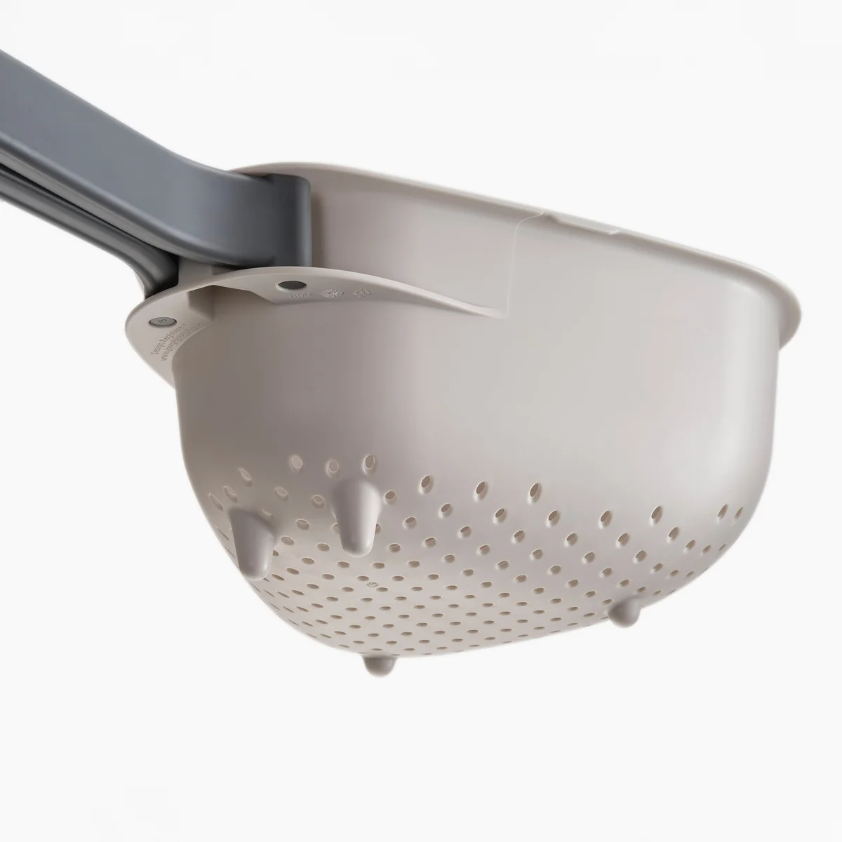 Primo piano di uno scolapasta bianco con manico grigio. Lo scolapasta è ovale, forato e ha tre piedi.