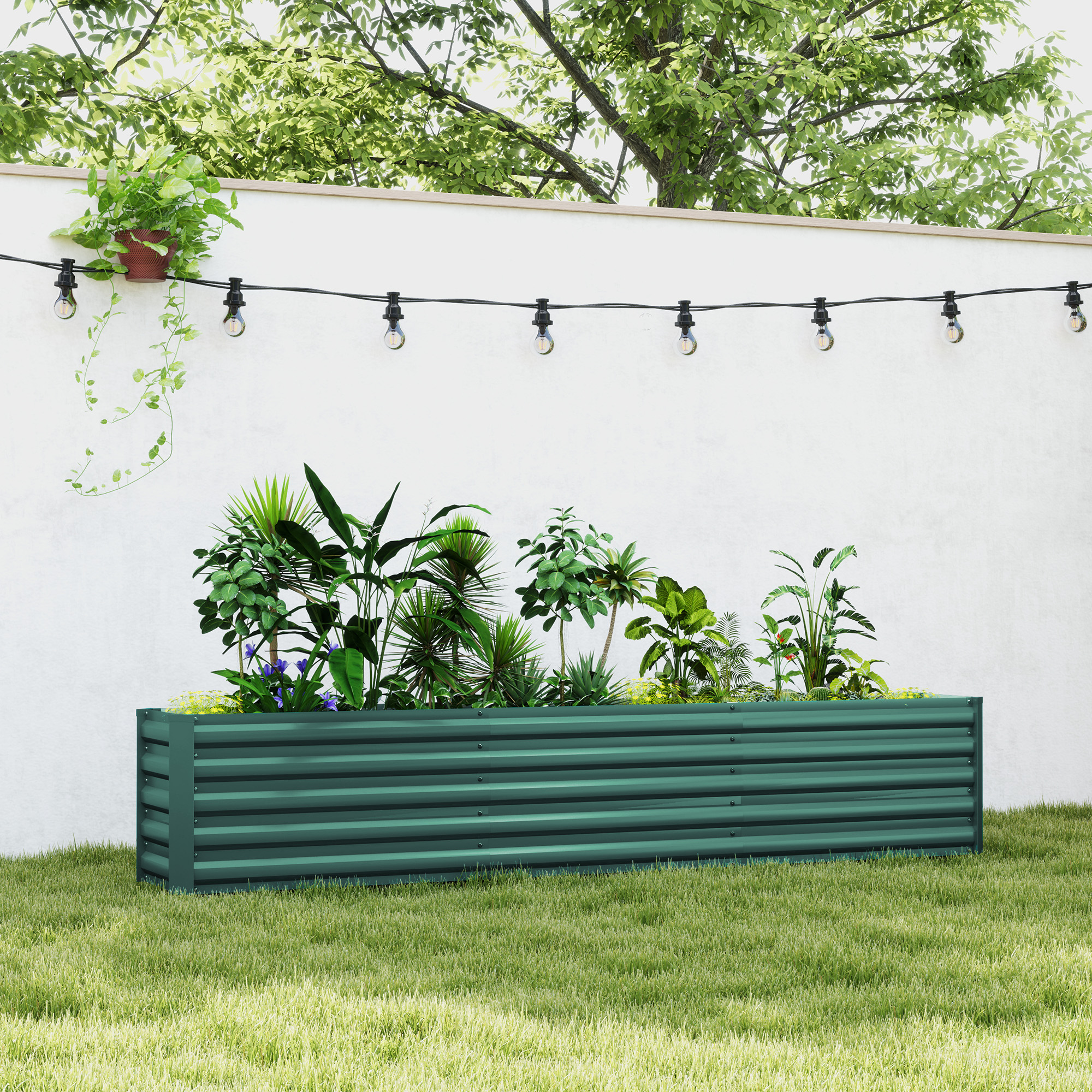 Una fioriera verde con varie piante si trova sull'erba. Un muro bianco con luci a stringa e una pianta pensile dietro.