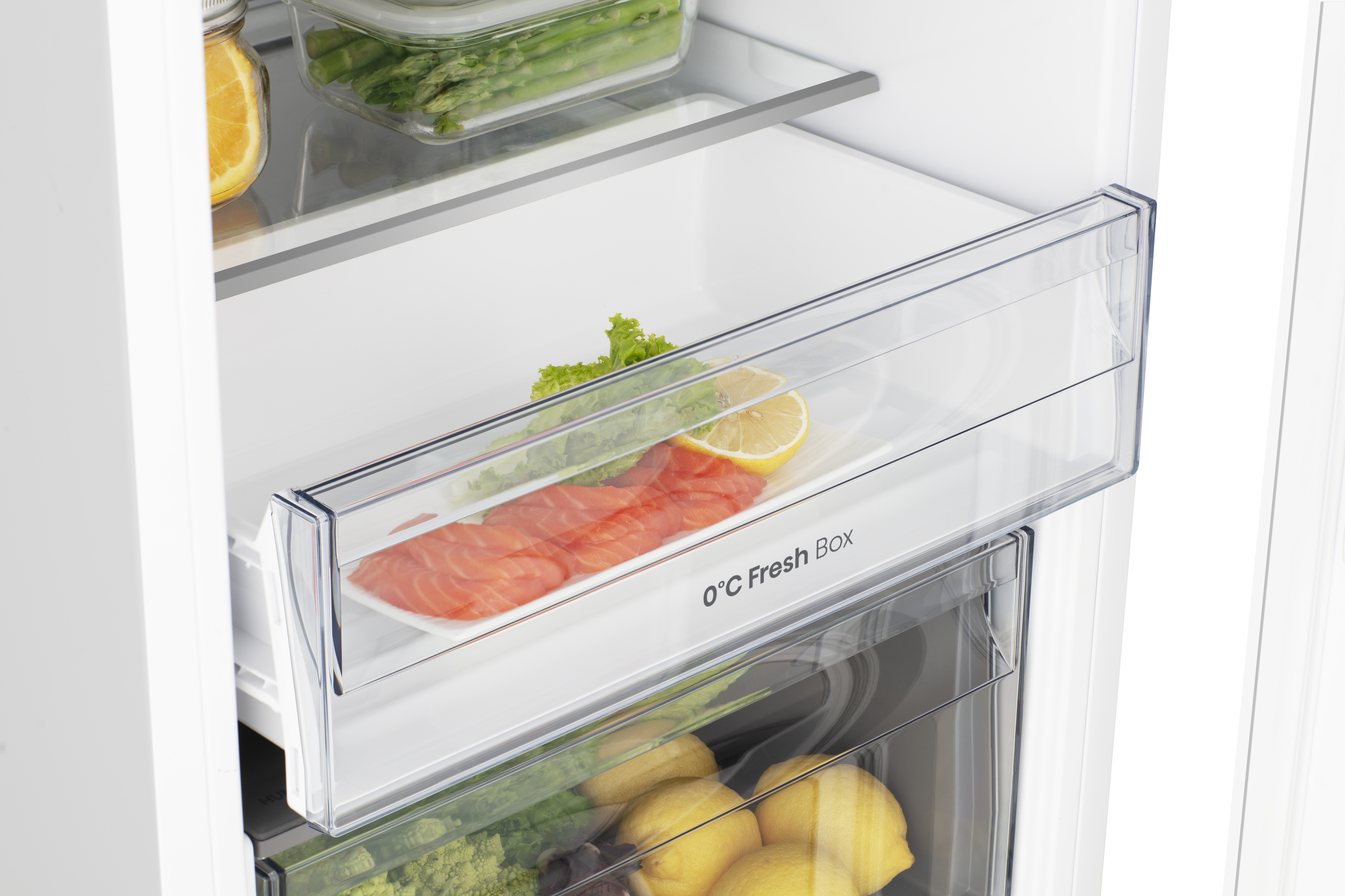 Wnętrze lodówki z łososiem, cytryną, sałatą, szparagami i plasterkami pomarańczy. Widoczna etykieta 0°C Fresh Box.