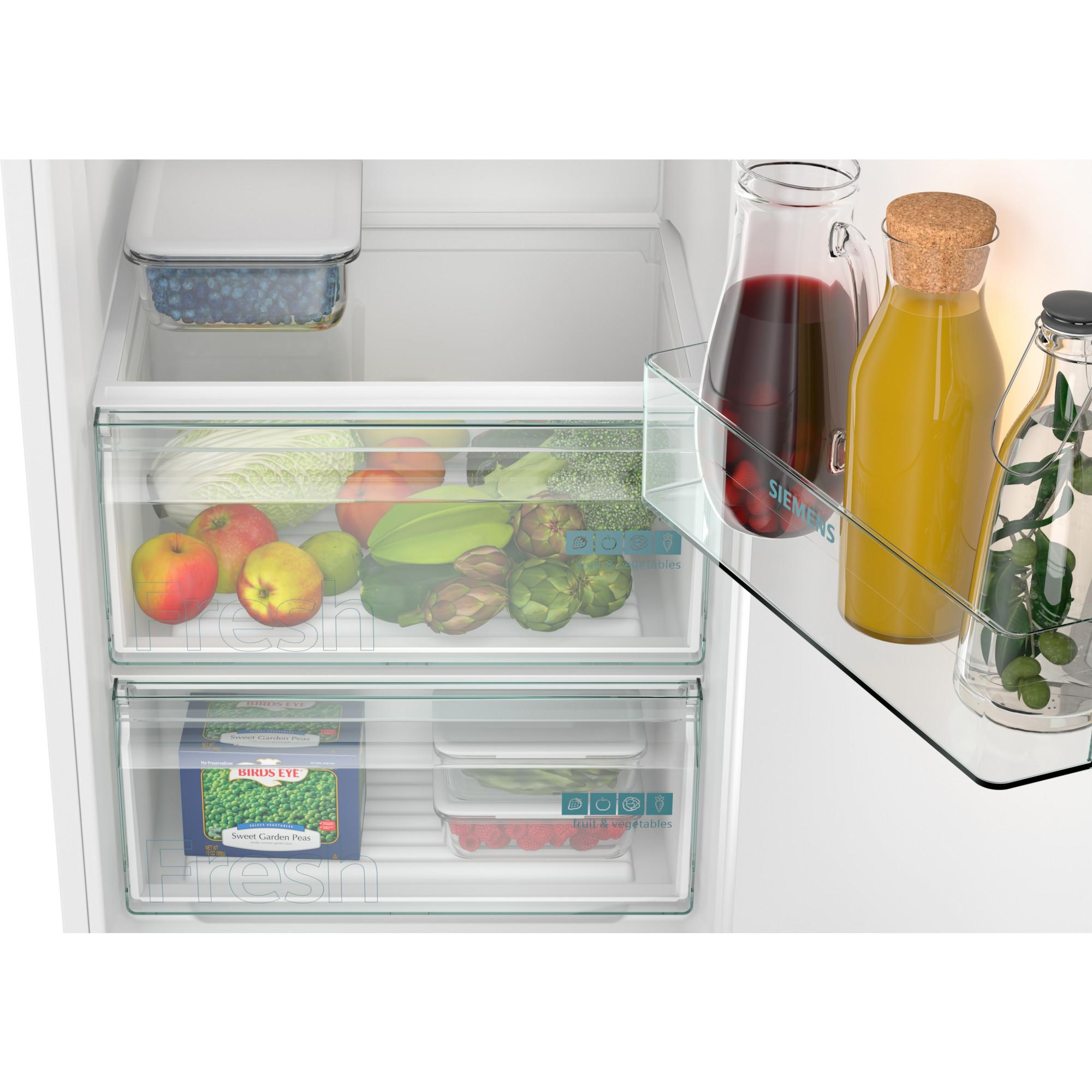 Koelkastinterieur met fruit en groenten. Inclusief appels, artisjokken, erwten, frambozen en drankjes in flessen.