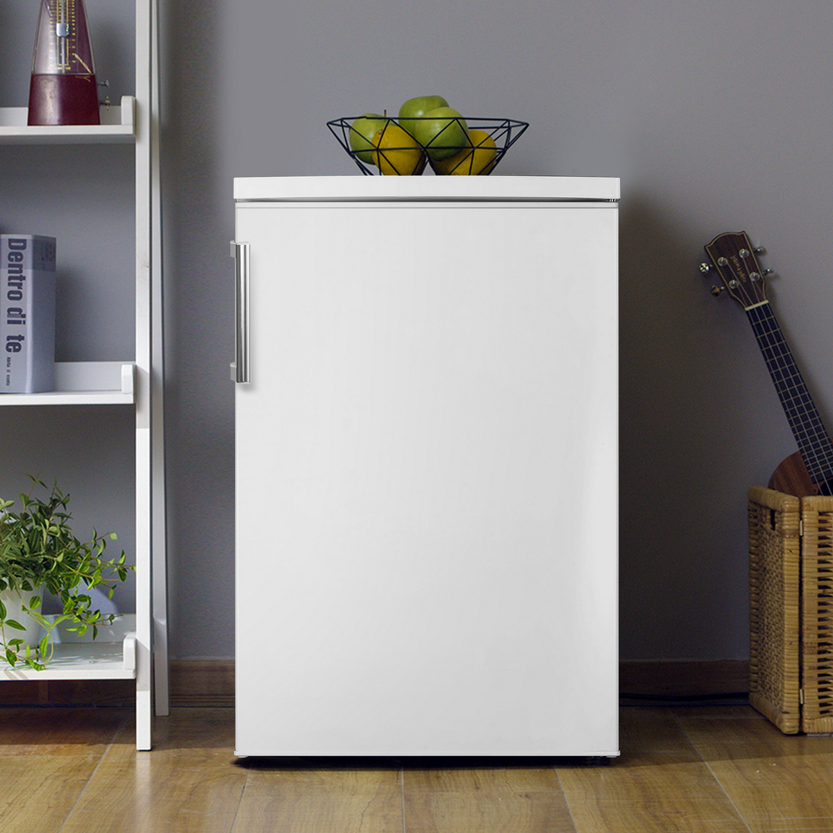 Biała lodówka z koszem owoców na górze, gitarą i wiklinowym koszem po prawej oraz półką z roślinami po lewej.
