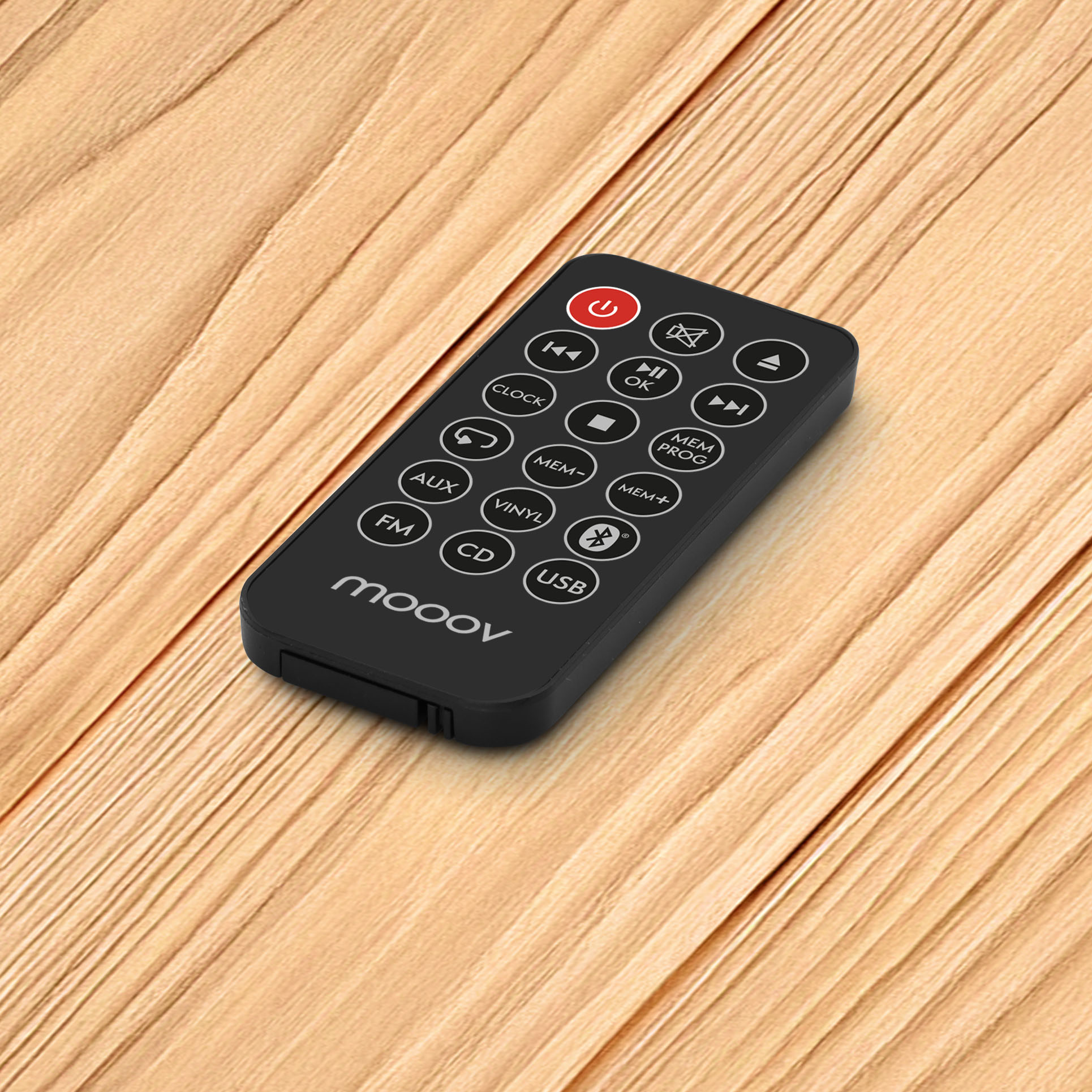 Mando a distancia negro con varios botones, incluyendo encendido y volumen, sobre una superficie de madera. Marca mooov.
