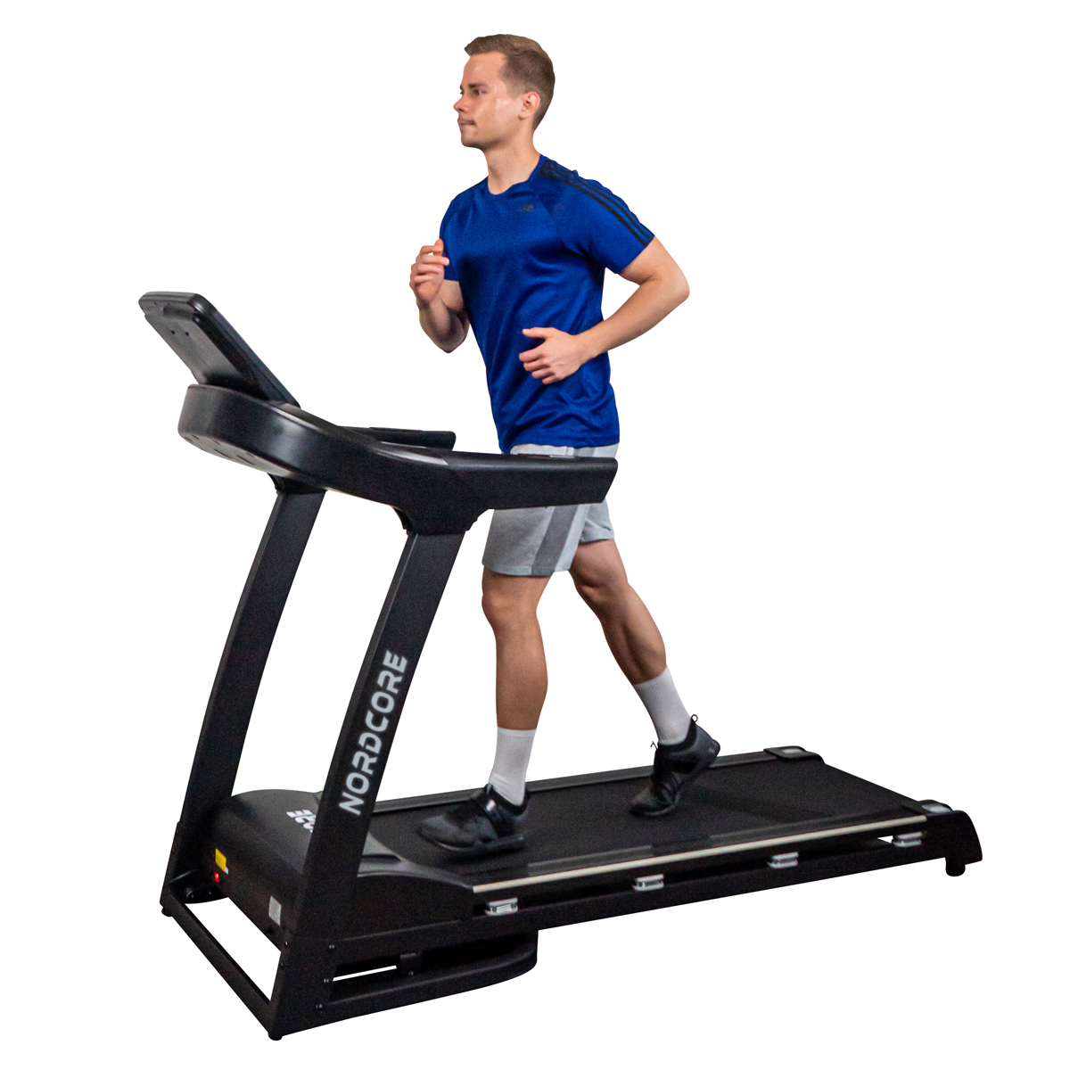 Mężczyzna w niebieskiej koszulce i szortach biega na czarnej bieżni. Bieżnia ma napis NORDCORE.