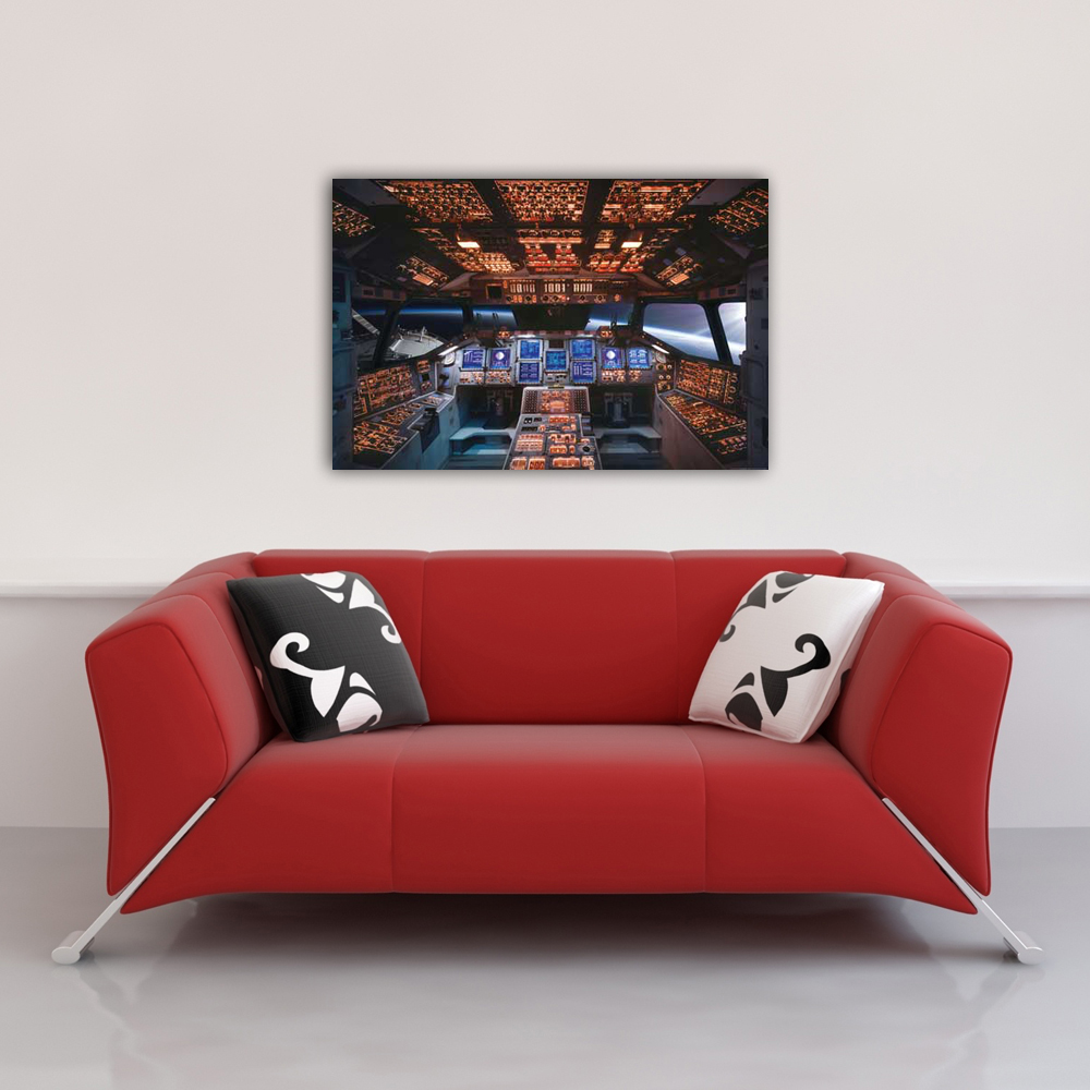Ein rotes Sofa mit zwei Kissen steht unter einem Bild eines Raumschiff-Cockpits. Das Bild zeigt viele Knöpfe und Bildschirme.