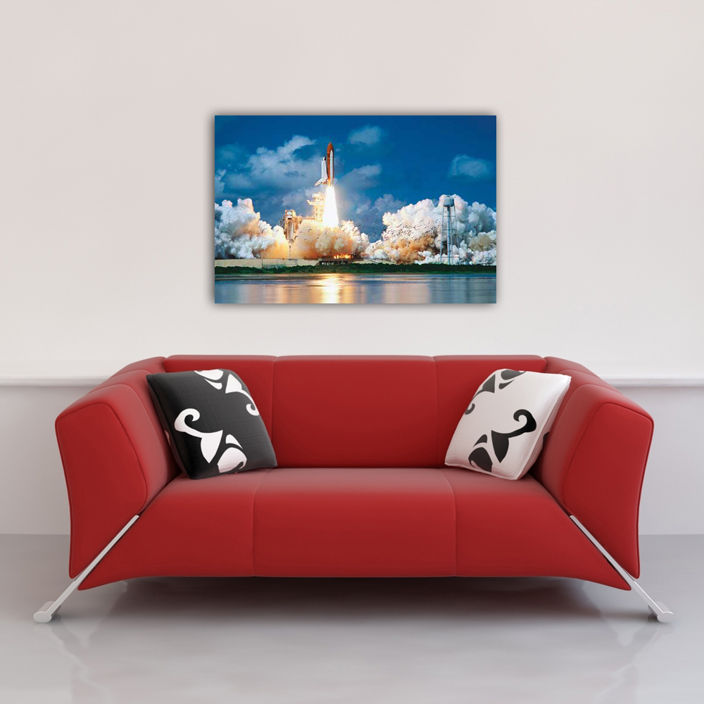 Rotes Sofa mit Kissen unter einem Bild eines startenden Raumschiffs. Die Rakete hat Flammen und Rauch. Blauer Himmel im Hintergrund.