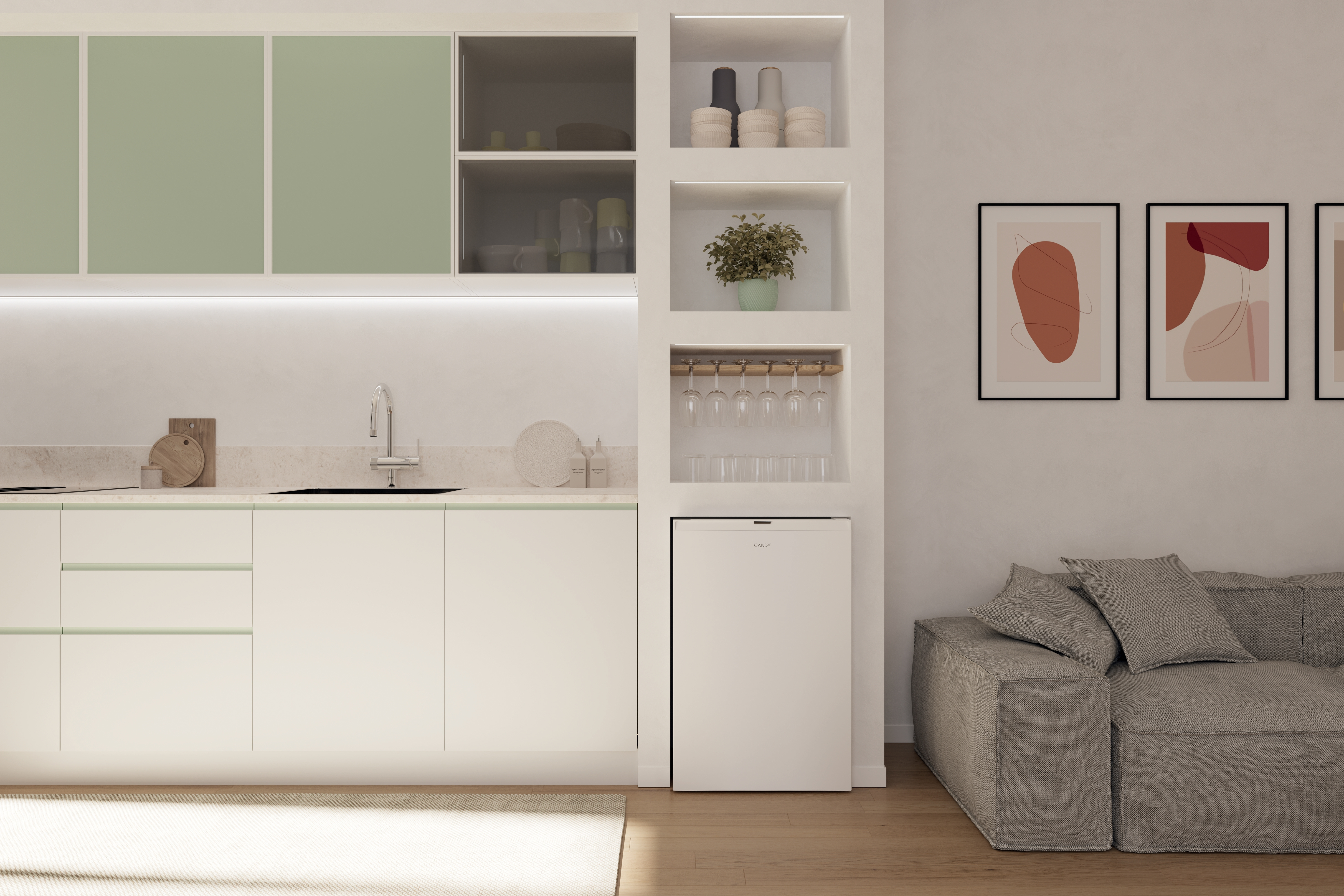 Nowoczesna kuchnia z białymi szafkami, zielonymi akcentami i abstrakcyjną sztuką. Szara sofa po prawej.