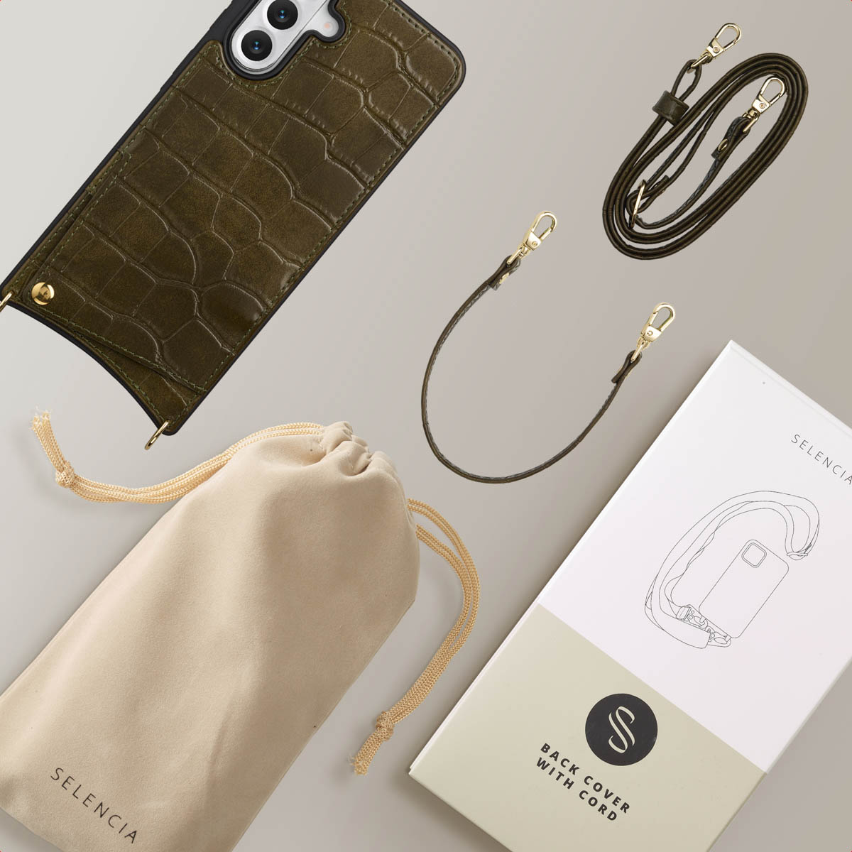 Custodia per telefono verde oliva con cinturino e accessori. Include una custodia, una scatola e un cinturino lungo. Tutto è posto su una superficie grigia.