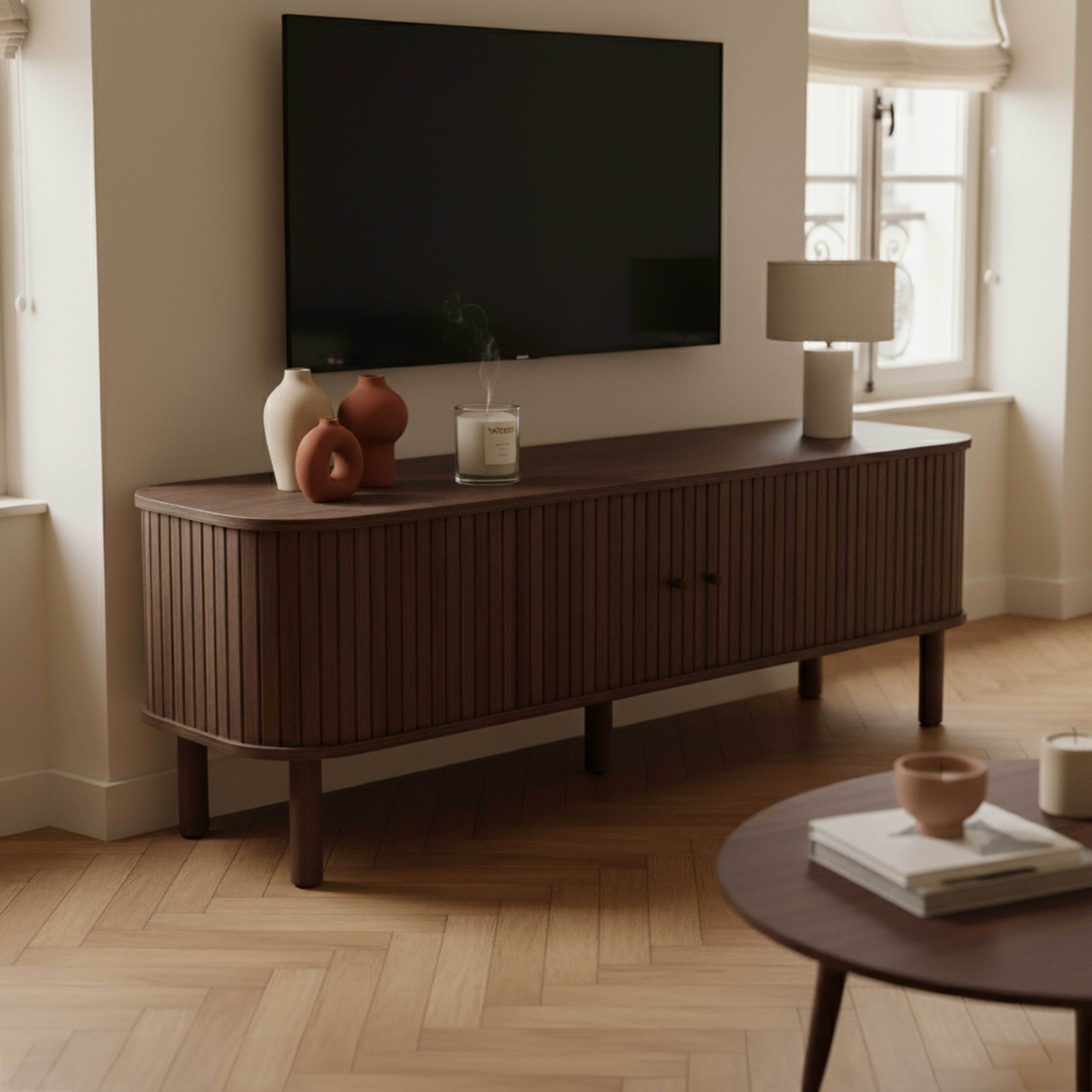 Ein modernes Wohnzimmer mit Fernseher, Holzschrank, Vasen und einem runden Couchtisch. Holzboden und Fenster.