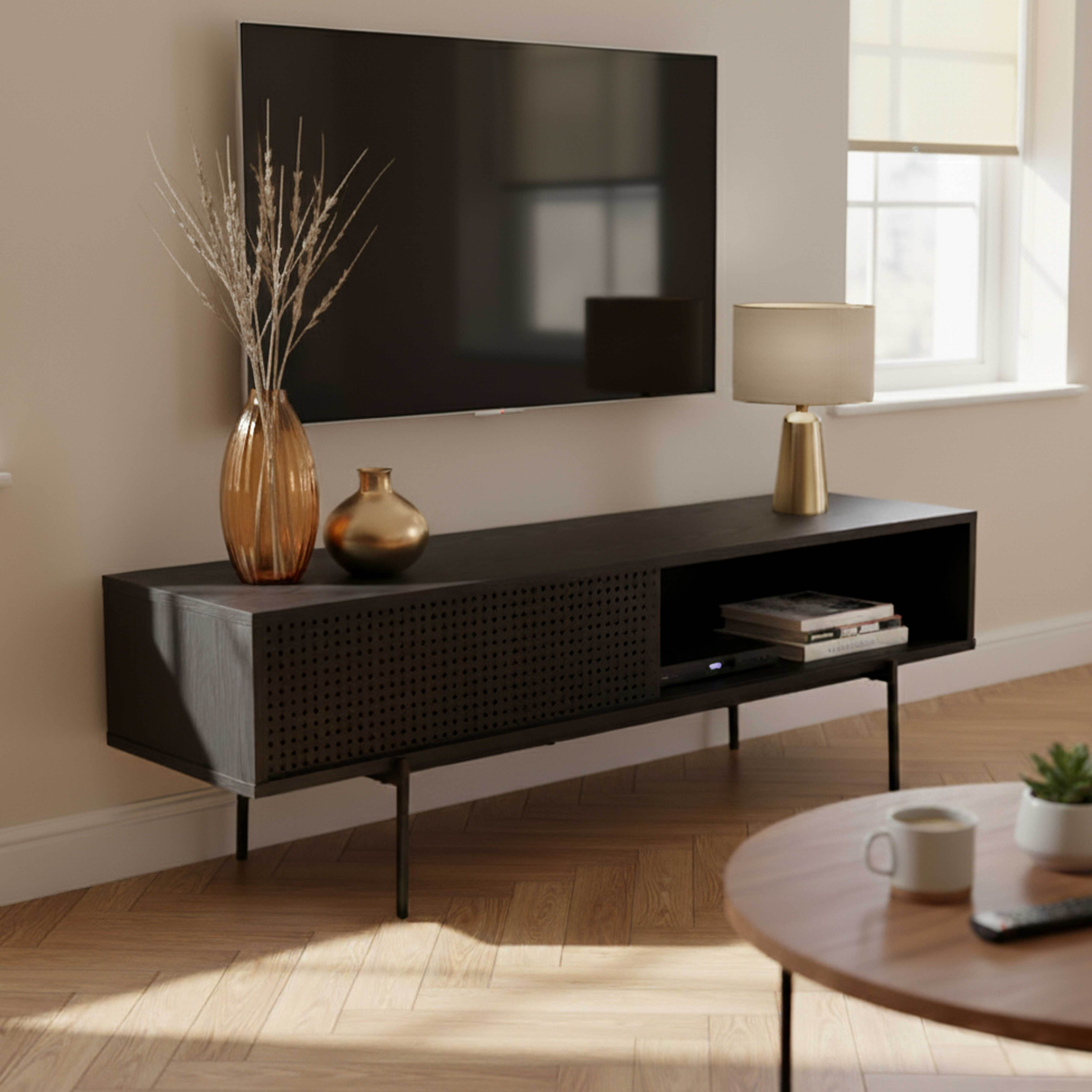 Ein modernes Wohnzimmer mit Fernseher, dunklem Holzschrank, rundem Tisch und Fenster.