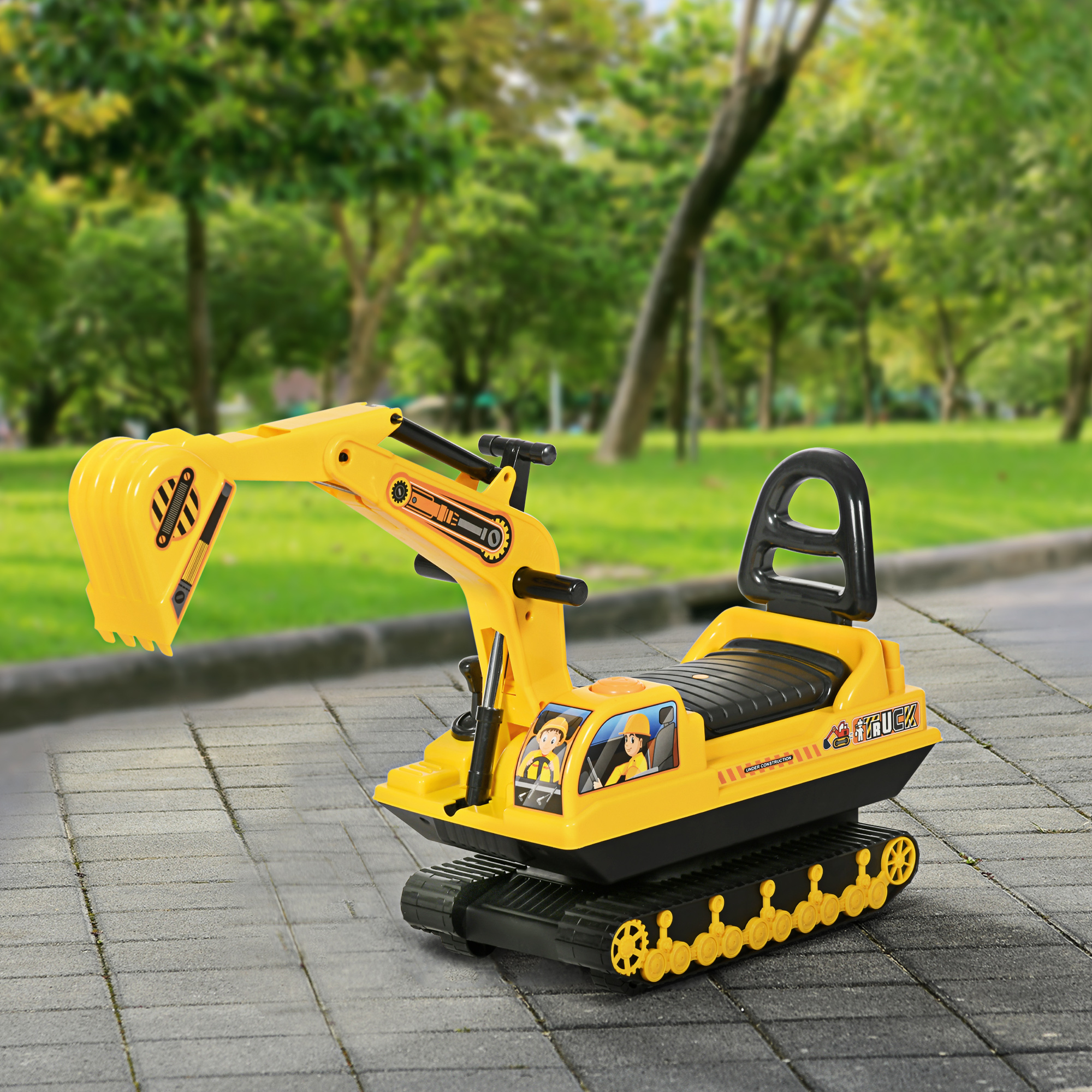 Un escavatore giocattolo giallo su una superficie pavimentata, con un parco sullo sfondo sfocato. Due figure sono nella cabina.