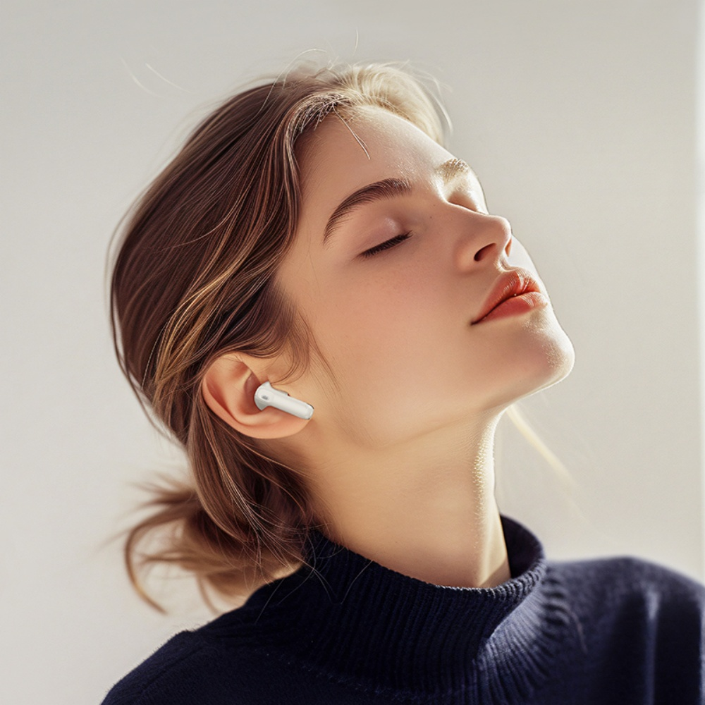 Una mujer con los ojos cerrados usando un auricular blanco. Tiene cabello castaño y una parte superior azul oscuro. El fondo es claro.