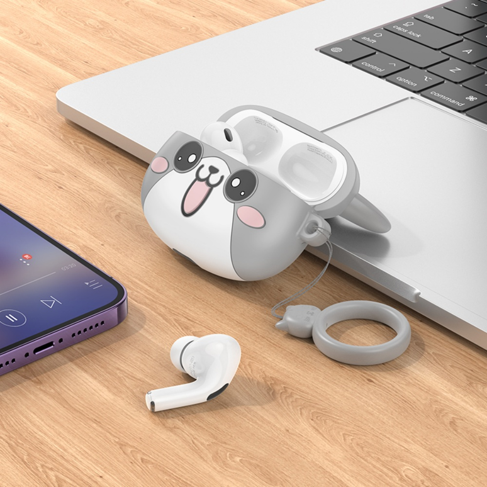 Auriculares y una funda con forma de animal de dibujos animados sobre una superficie de madera cerca de un port átil y un teléfono.