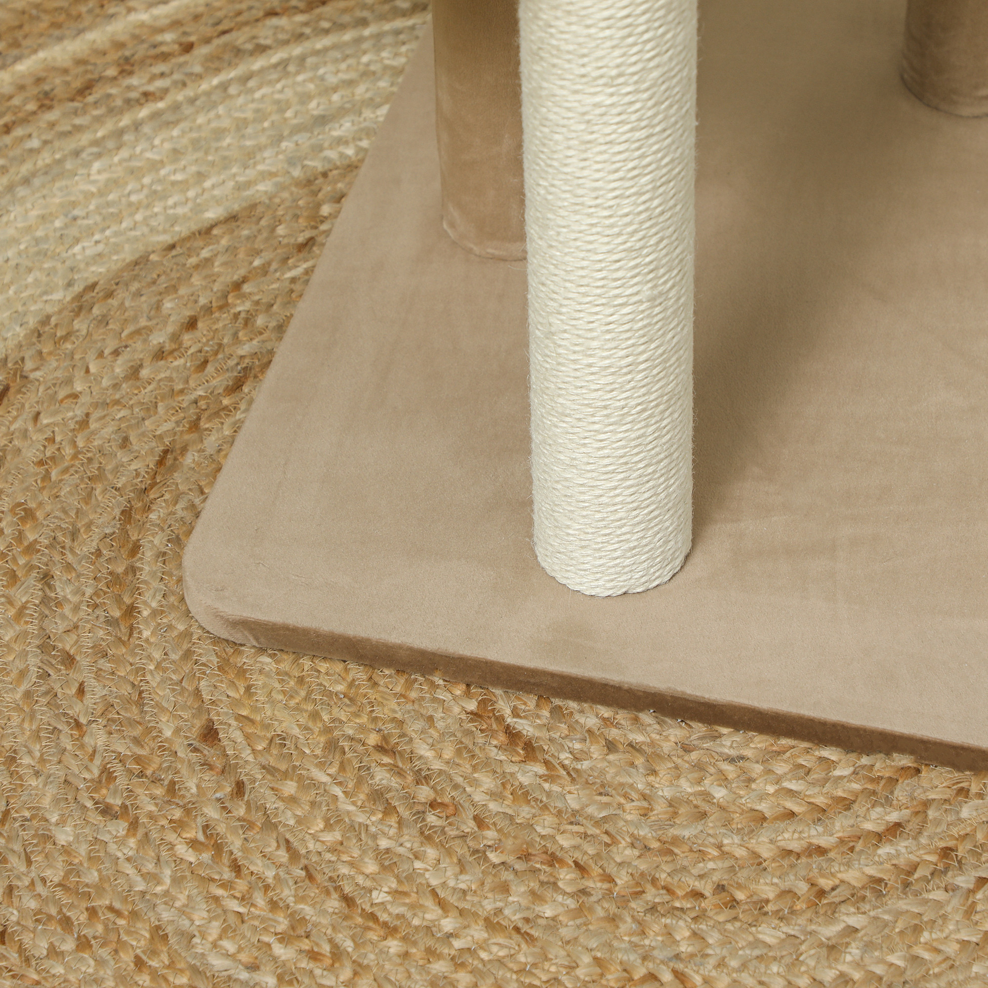 Primer plano de un árbol para gatos con plataformas beige y un poste rascador de sisal tejido, sobre una alfombra de yute.