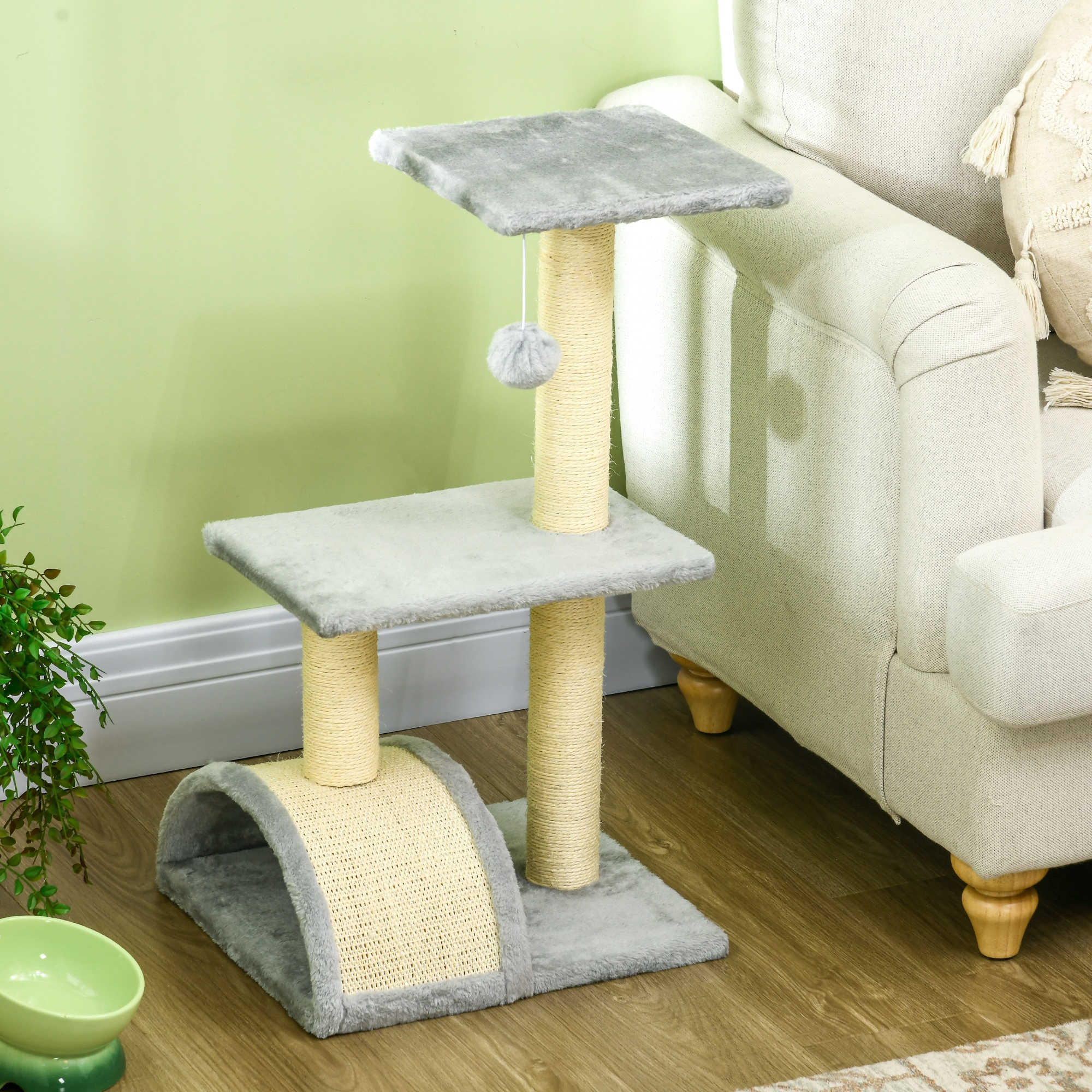 Un rascador para gatos con plataformas grises, postes beige y un pompón gris, sobre piso de madera.