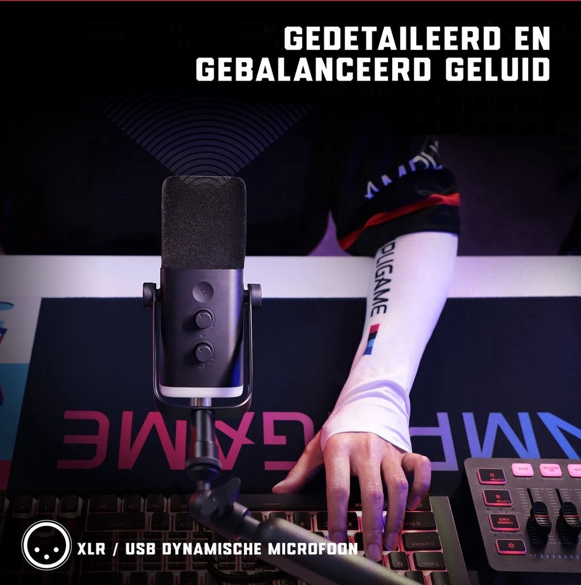 Een zwarte microfoon staat voor een toetsenbord. De arm van een persoon is zichtbaar, met een witte mouw. De achtergrond is een gaming-setup met een mat.