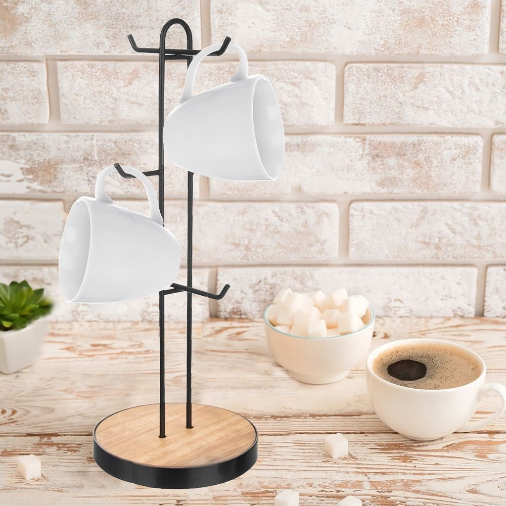 Un estante para tazas con dos tazas blancas. Cubos de azúcar y una taza de café sobre una mesa de madera. Pared de ladrillo al fondo.