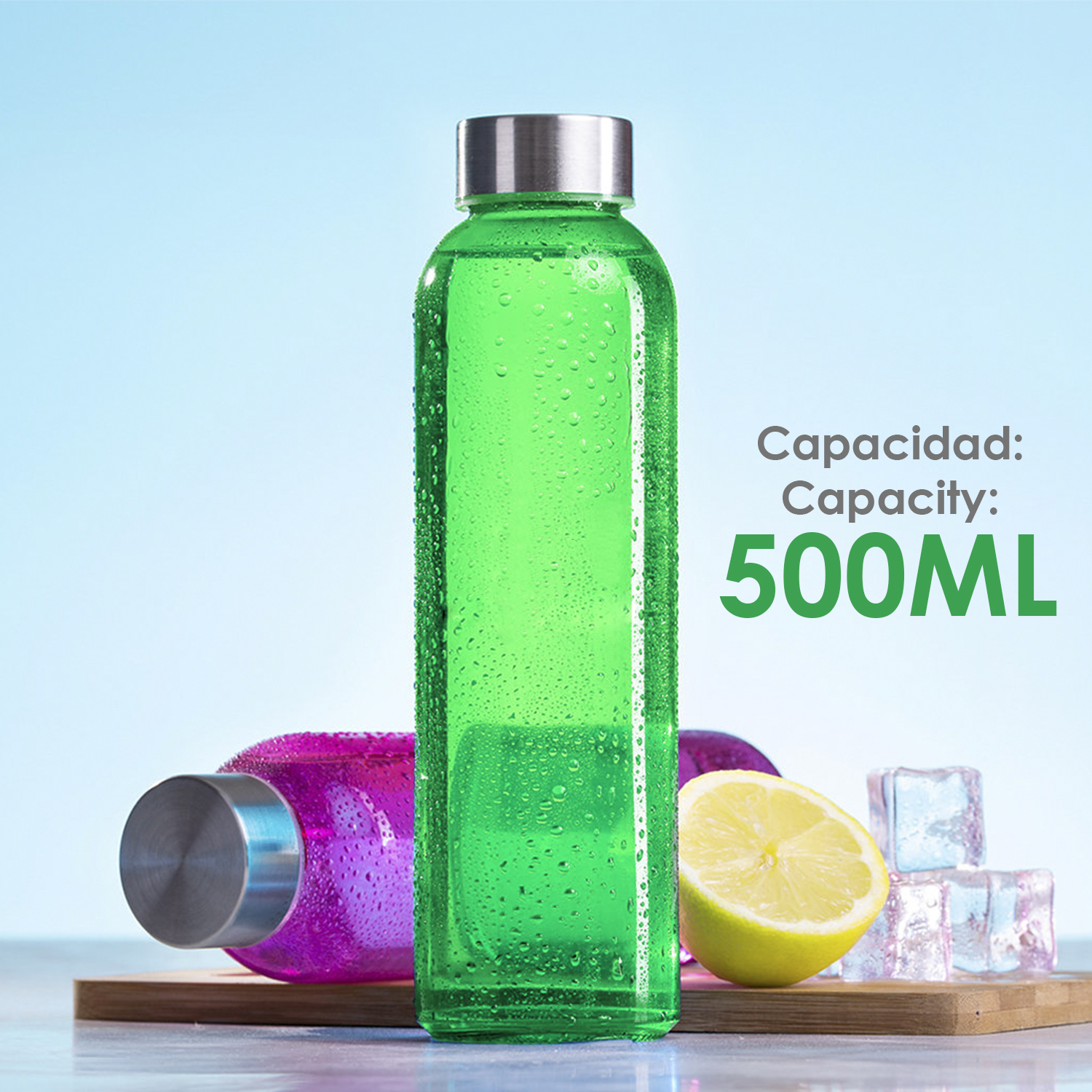 Una bottiglia d'acqua verde con tappo argentato è in piedi, una bottiglia rosa è dietro. Un limone e cubetti di ghiaccio sono su una tavola di legno.
