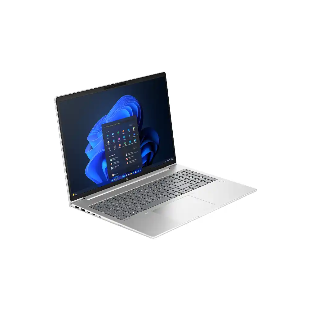 Gümüş dizüstü bilgisayar açık, Windows arayüzünü gösteriyor. Klavye ve dokunmatik yüzey görünür. Ekran mavi soyut tasarım ve uygulama simgeleri gösteriyor.