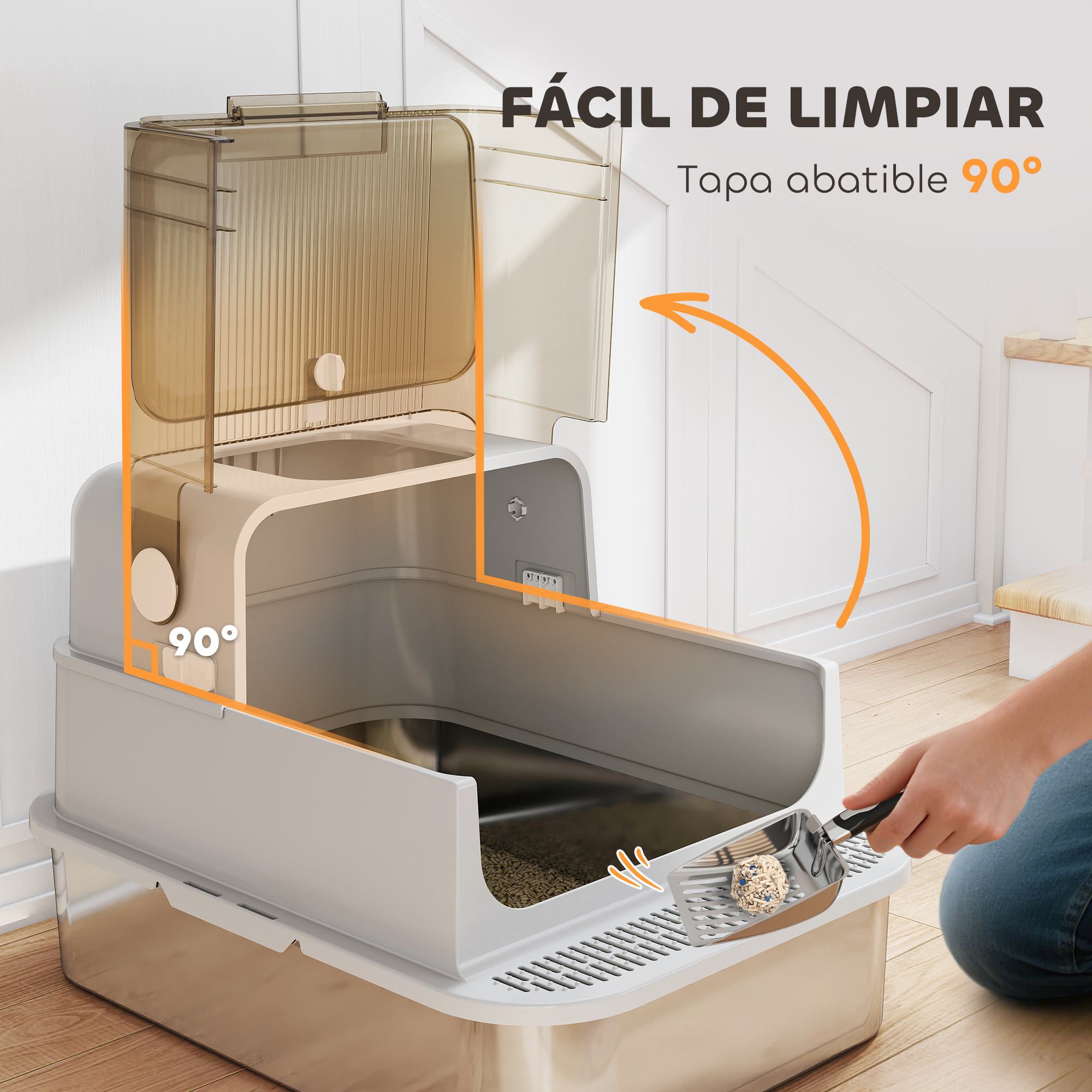 Una caja de arena para gatos con la tapa abierta, una persona está recogiendo la arena con una pala, pared blanca al fondo.
