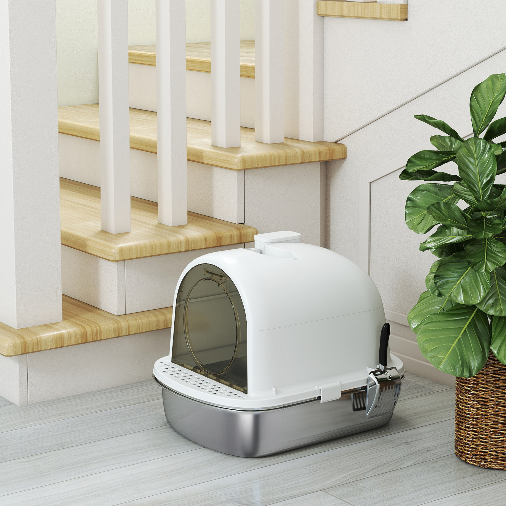 Un arenero blanco para gatos está junto a unas escaleras y una planta en maceta. Las escaleras tienen contrahuellas blancas y peldaños de madera.