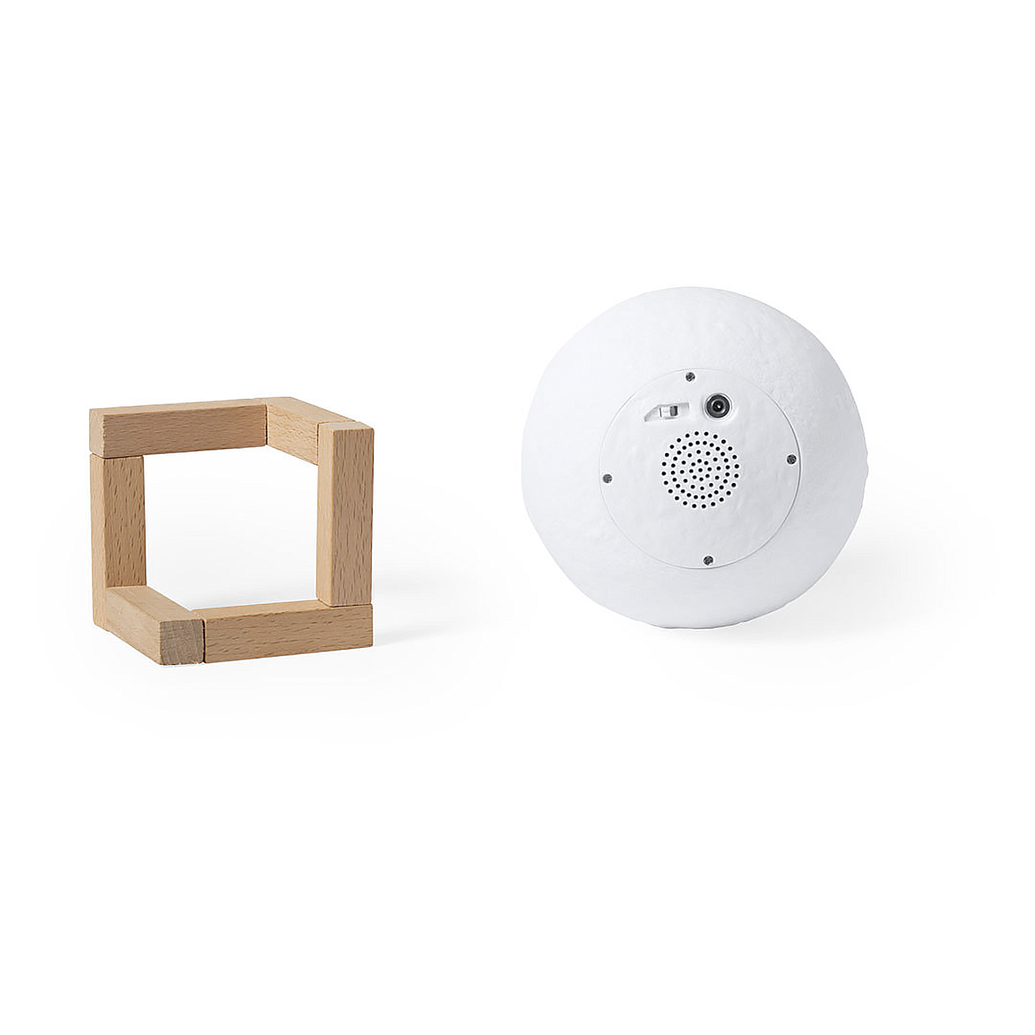 Un telaio cubico in legno e un oggetto sferico bianco con altoparlante e porta di alimentazione su una superficie bianca.