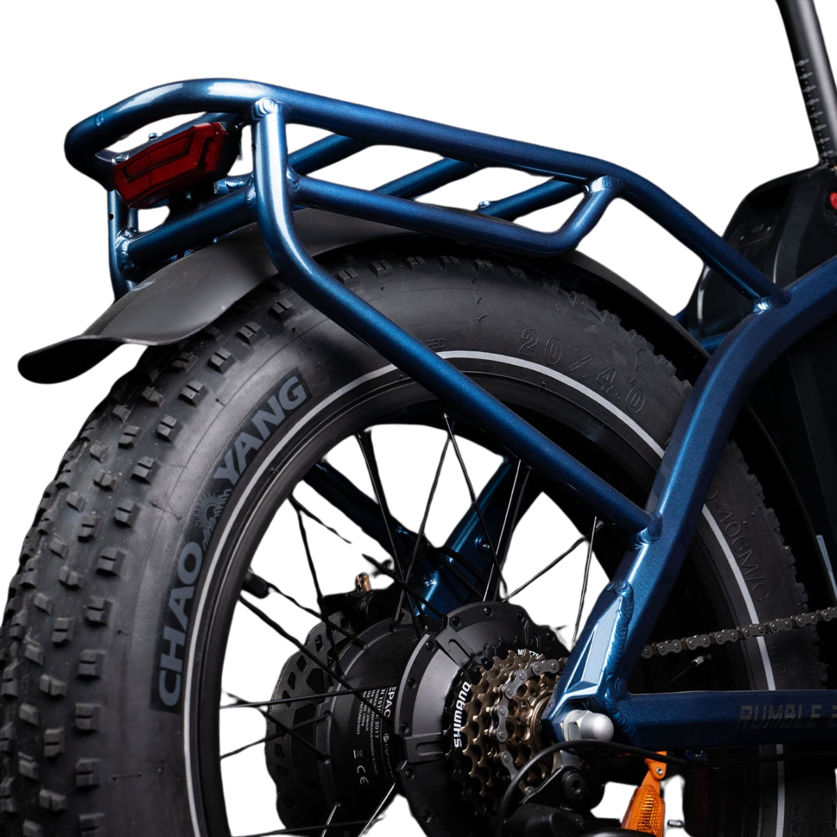 Zbliżenie niebieskiego roweru elektrycznego. Widoczna tylna opona z nazwą marki 'CHAO YANG'. Niebieski bagażnik i czerwone światło tylne.