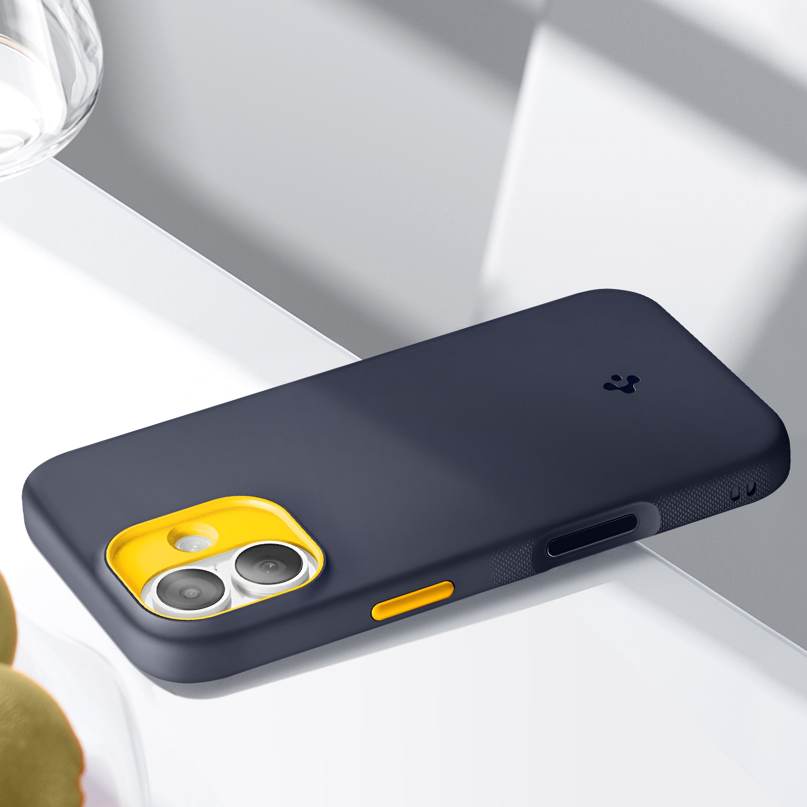 Una custodia per telefono blu scuro con un ritaglio giallo per la fotocamera, su una superficie bianca.