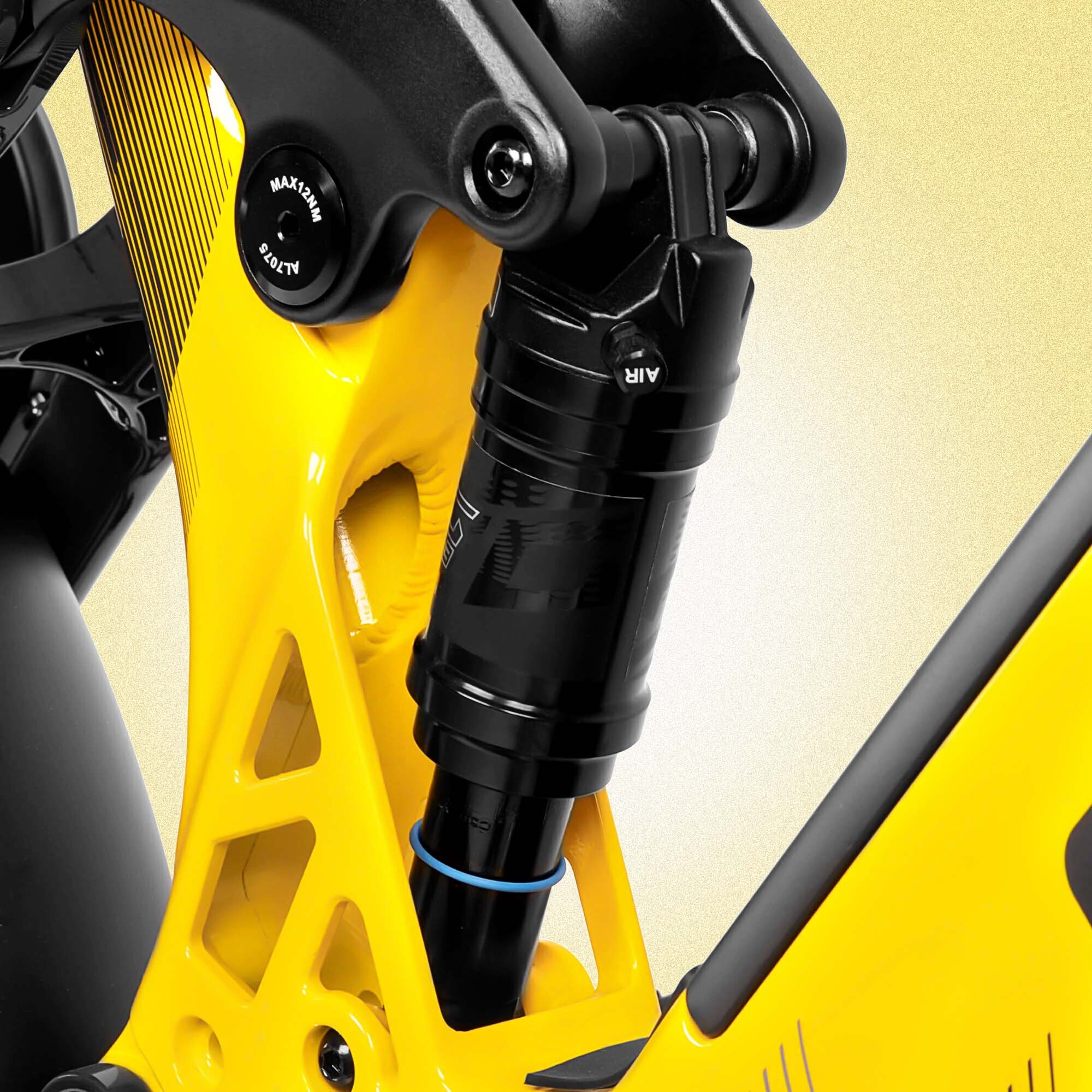 Zbliżenie żółto-czarnego amortyzatora roweru. Tło to gradient żółto-biały.