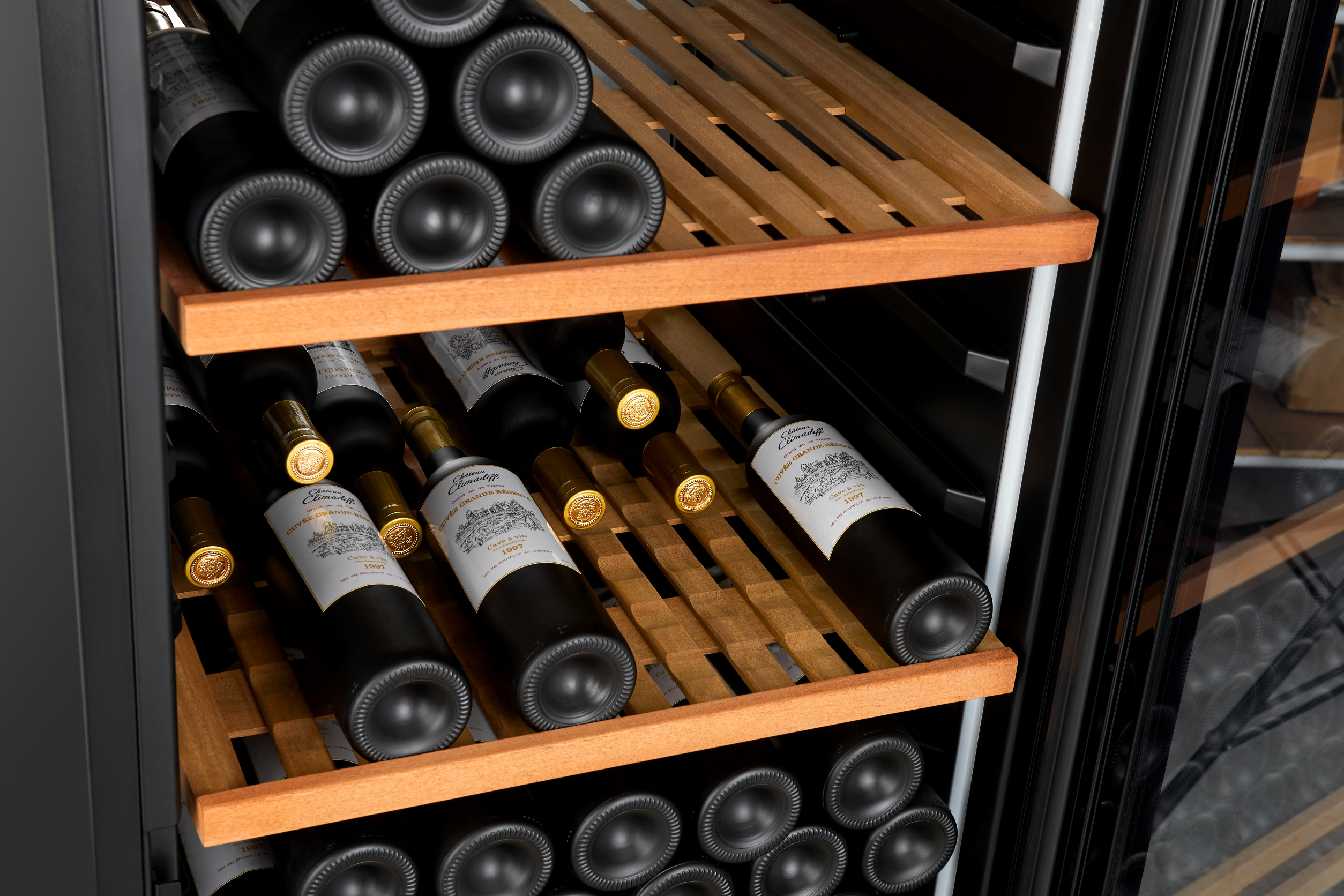 Botellas de vino almacenadas en un enfriador. Botellas en estantes de madera. Algunas etiquetadas Chateau Climadiff.