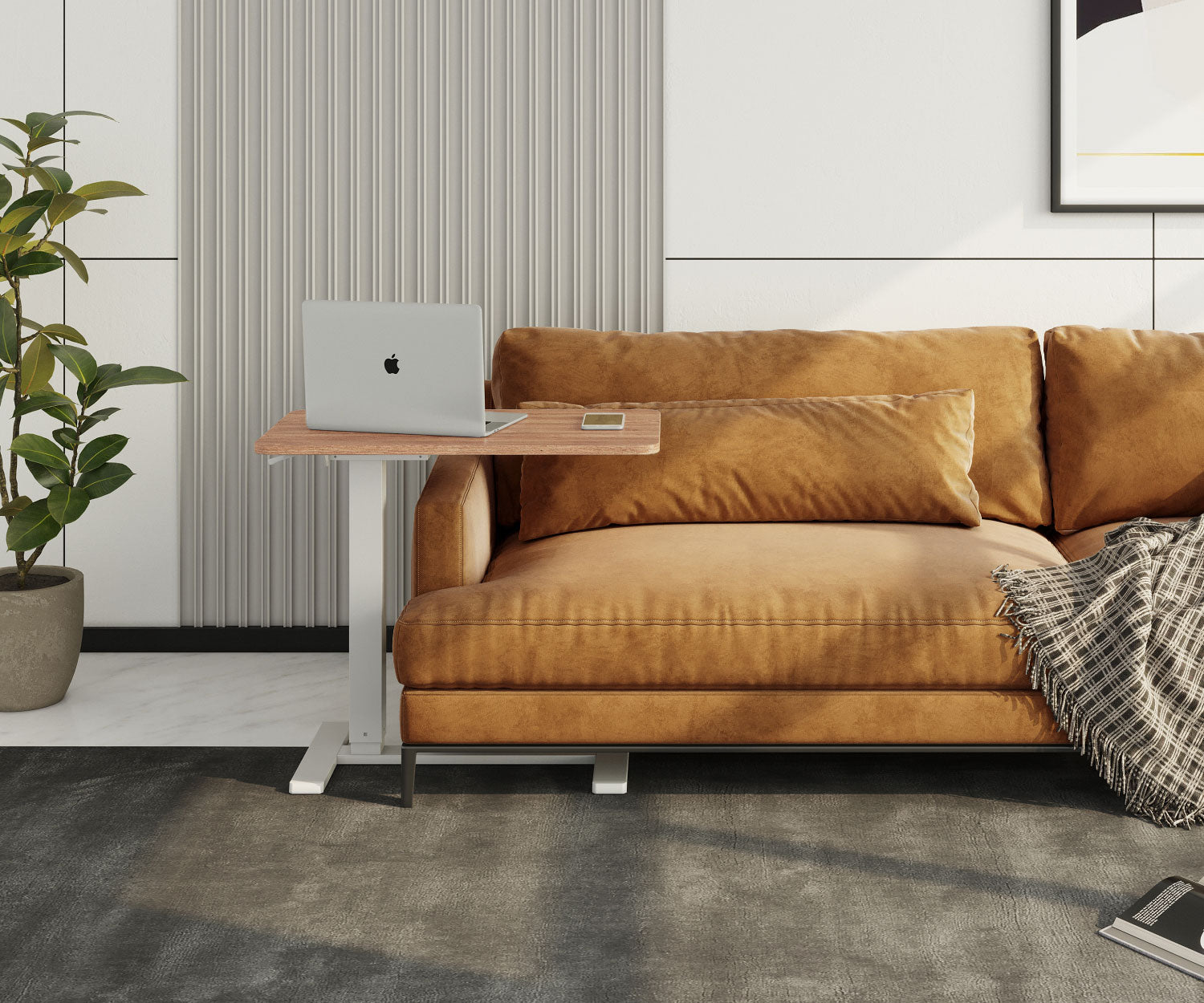 Ein Laptop auf einem Holztisch neben einem braunen Ledersofa. Links ist eine Pflanze. Eine karierte Decke auf dem Sofa.
