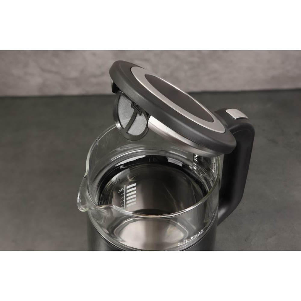 Przezroczysty szklany czajnik elektryczny z czarną pokrywą i uchwytem. Pokrywa jest otwarta, odsłaniając filtr siatkowy. Woda w środku.